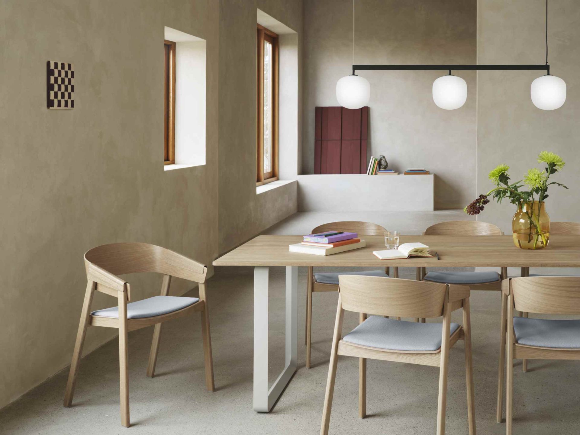 Esszimmer mit Esstisch, Stühlen und Rime Rail Pendelleuchte von Muuto mit drei Leuchtkörpern.