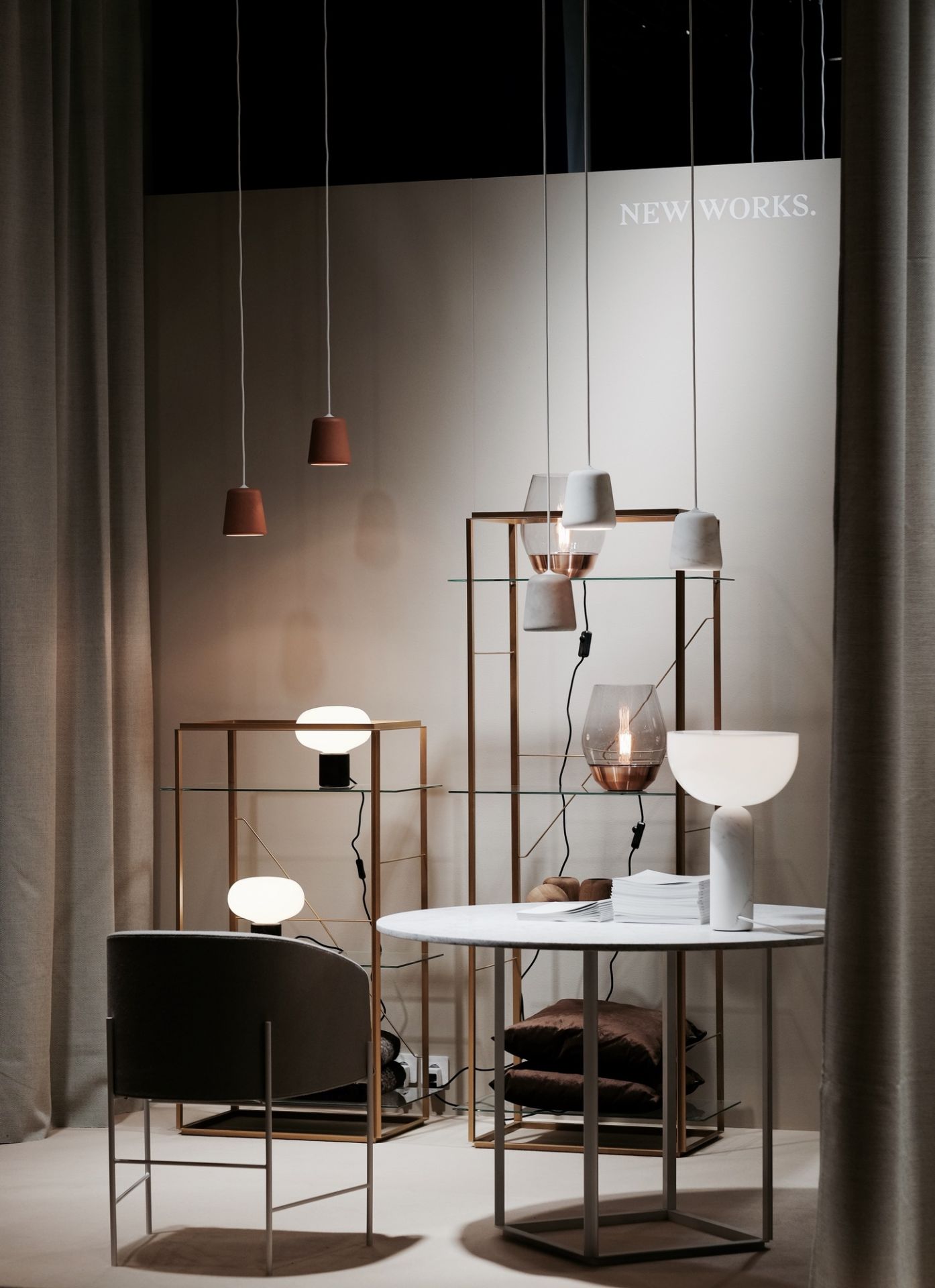 Ausstellung mit New Works Karl-Johan Tischleuchte und Pendelleuchten auf einem Tisch und Regal.