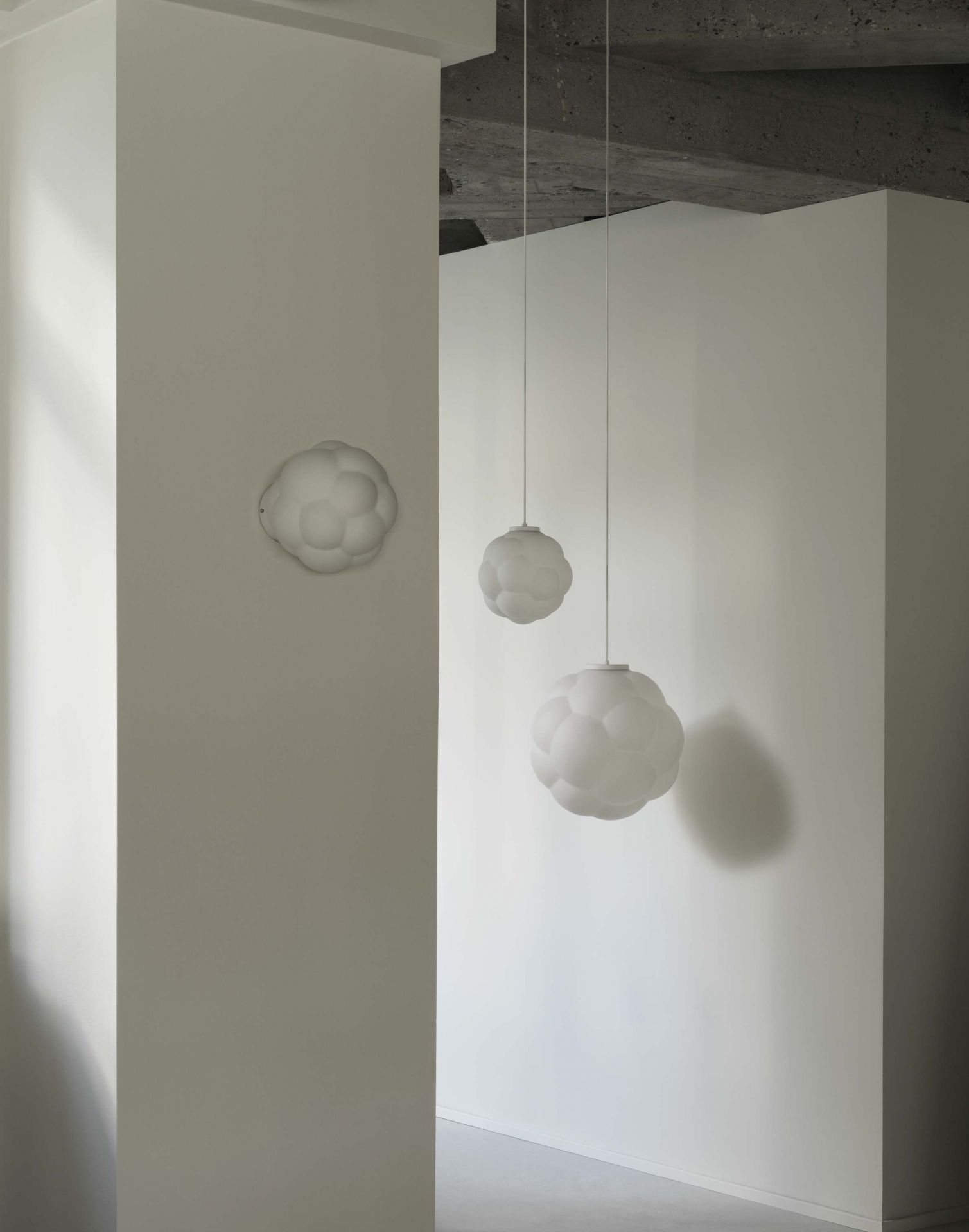 Zwei Bubba Pendelleuchten von Normann Copenhagen, weiße Design-Hängelampen und eine Wandleuchte.
