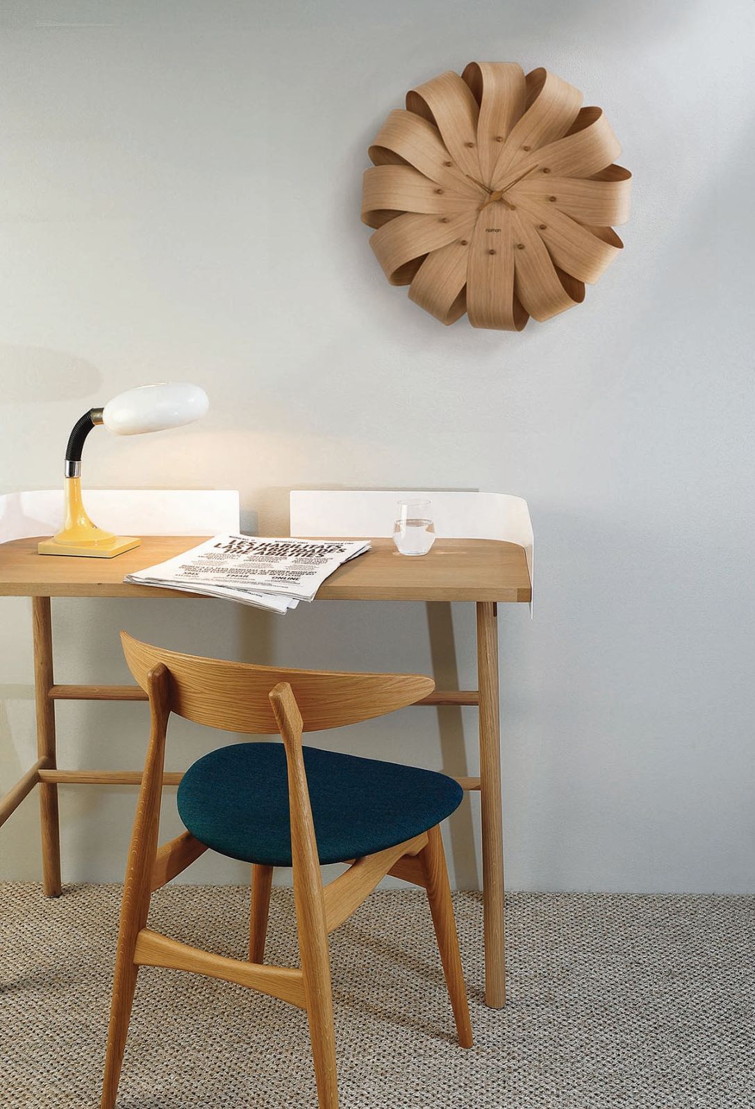 Brisa Wanduhr von Nomon, Ø52cm, aus Holz, über einem Schreibtisch mit Stuhl. Design Wanduhr.