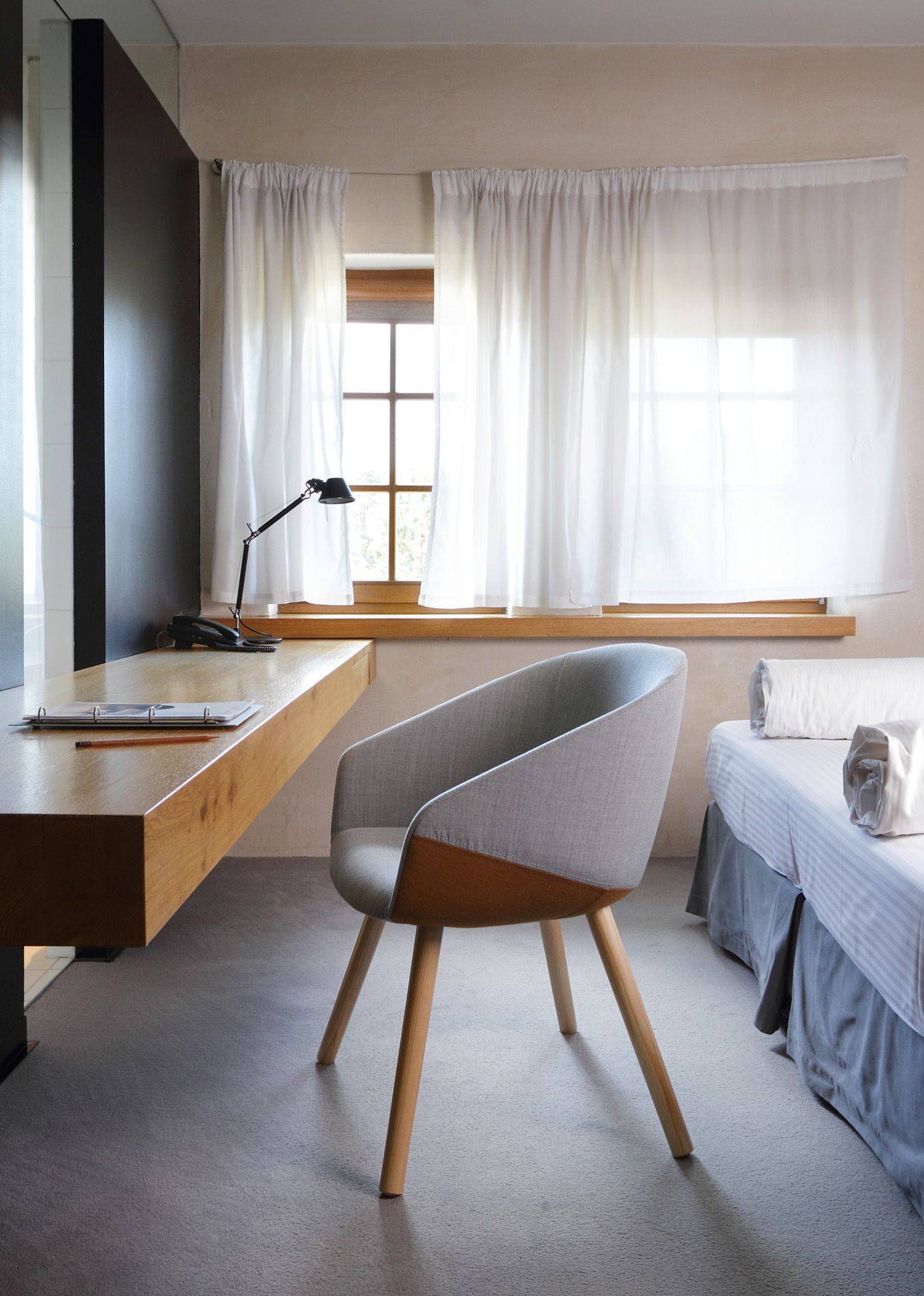ox:co OX W 740 Konferenzsessel Bejot mit grauem Stoffbezug und Holzbeinen in modernem Hotelzimmer.