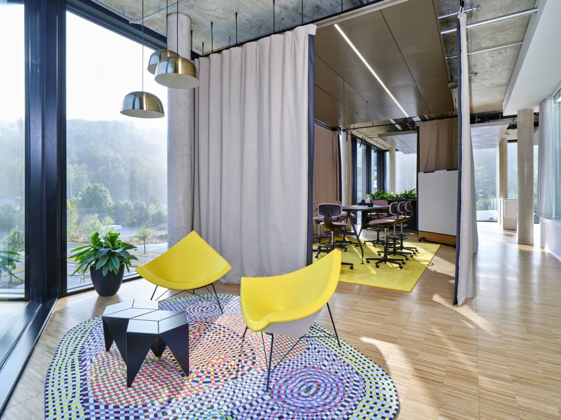 Gelbe Coconut Chairs von Vitra in modernem Büro mit Teppich und Besprechungsraum im Hintergrund.