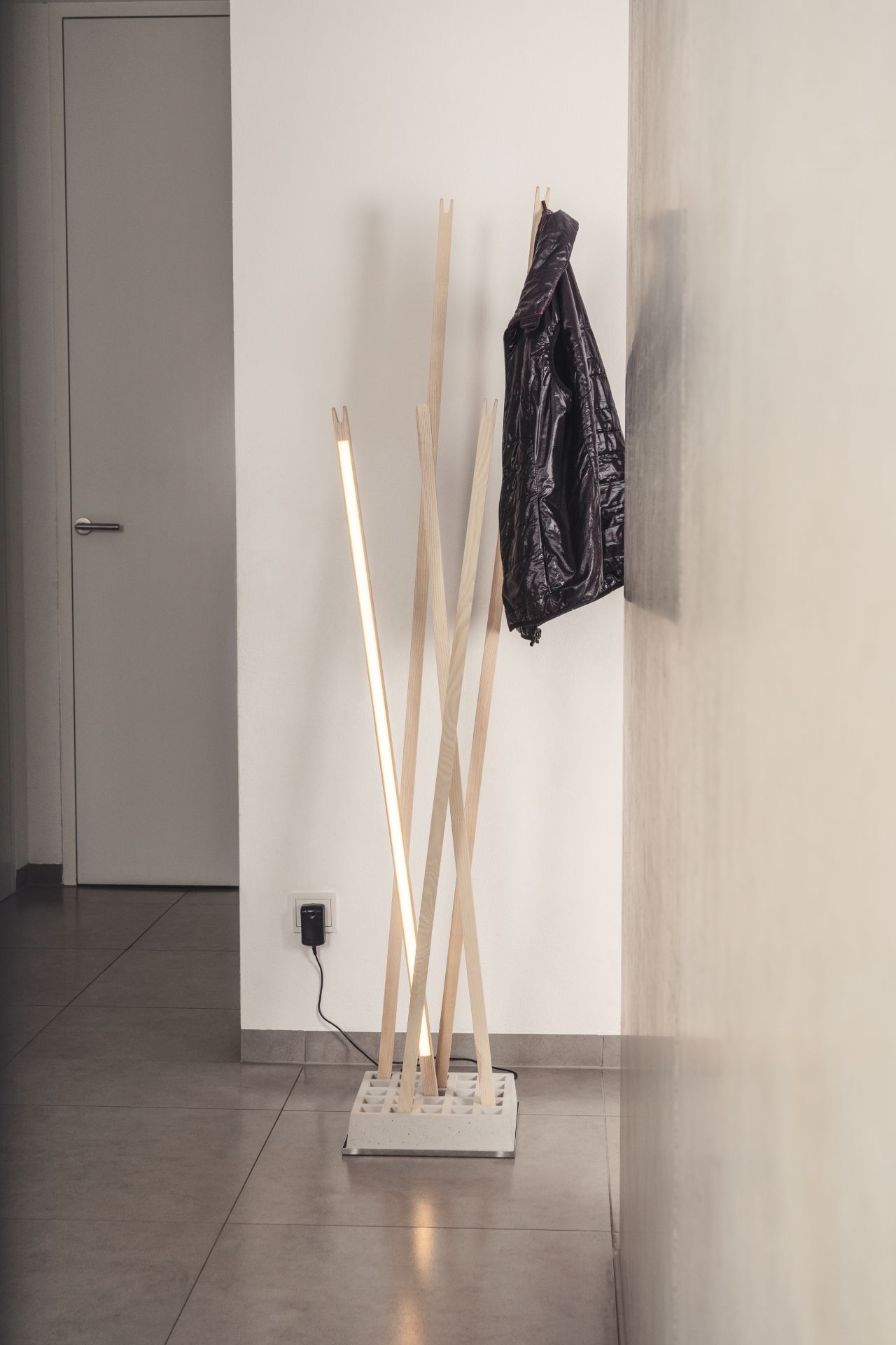 Moderne Garderobe mit Beleuchtung: Pin Coat Garderobe / Pin Light Leuchte von Nils Holger Moormann mit Jacke.