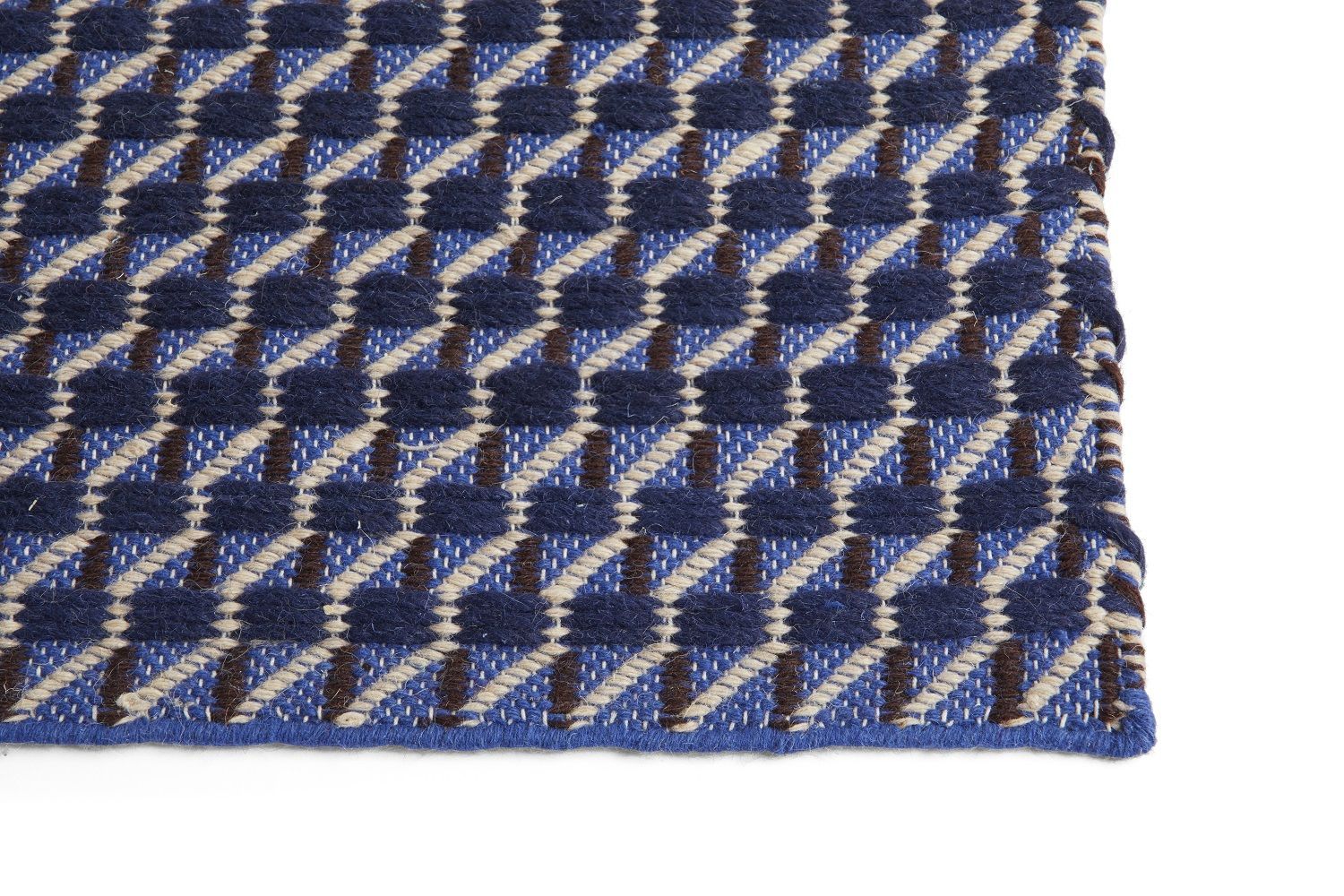 Detailaufnahme des blau-weißen Channel Rug Teppichs von Hay mit geometrischem Hahnentrittmuster für Wohnzimmer und Schlafzimmer.