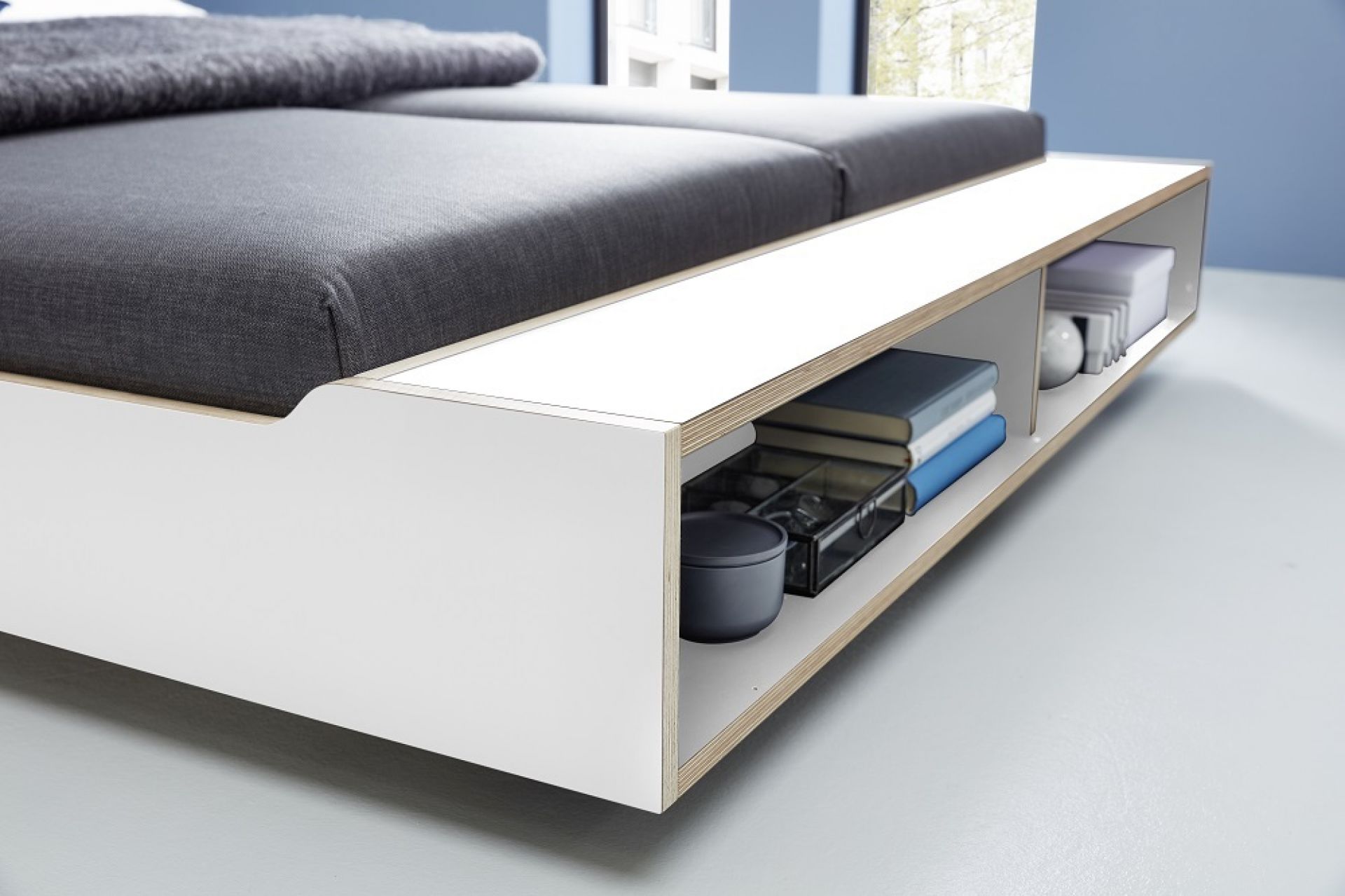 Detailaufnahme vom Maude Bett von Müller Möbelwerkstätten mit Stauraum und grauem Stoffbezug.