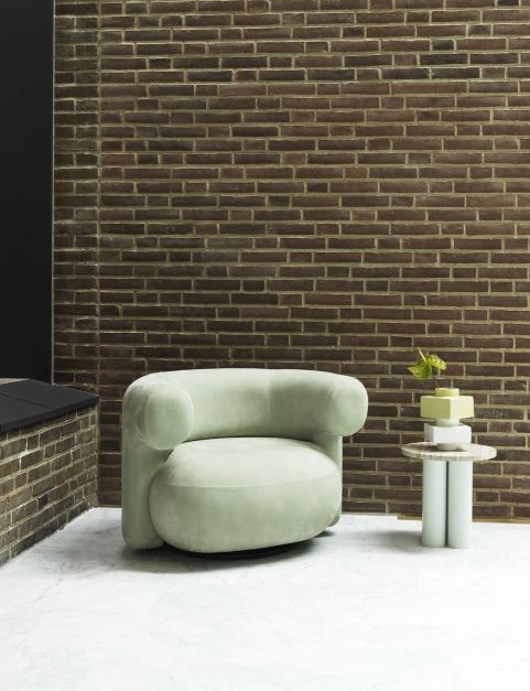 Heller Raum mit mintgrünem Sessel und Dit Coffee Table Beistelltisch von Normann Copenhagen vor einer Backsteinwand.