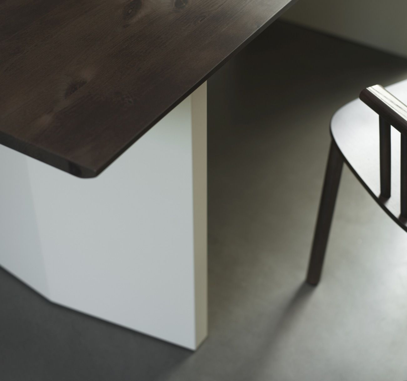 Detailaufnahme: Normann Copenhagen Panel Tisch, Esstisch mit dunkler Holzplatte und weißem Untergestell, Stuhl im Hintergrund.