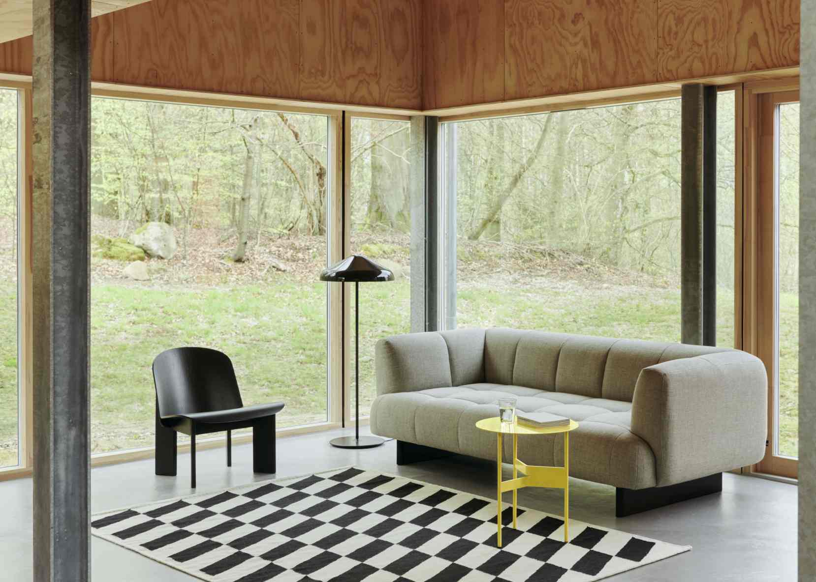 Heller Wohnraum mit Hay Quilton Sofa, Sessel, Stehlampe, gelbem Beistelltisch und Schachbrett-Teppich.