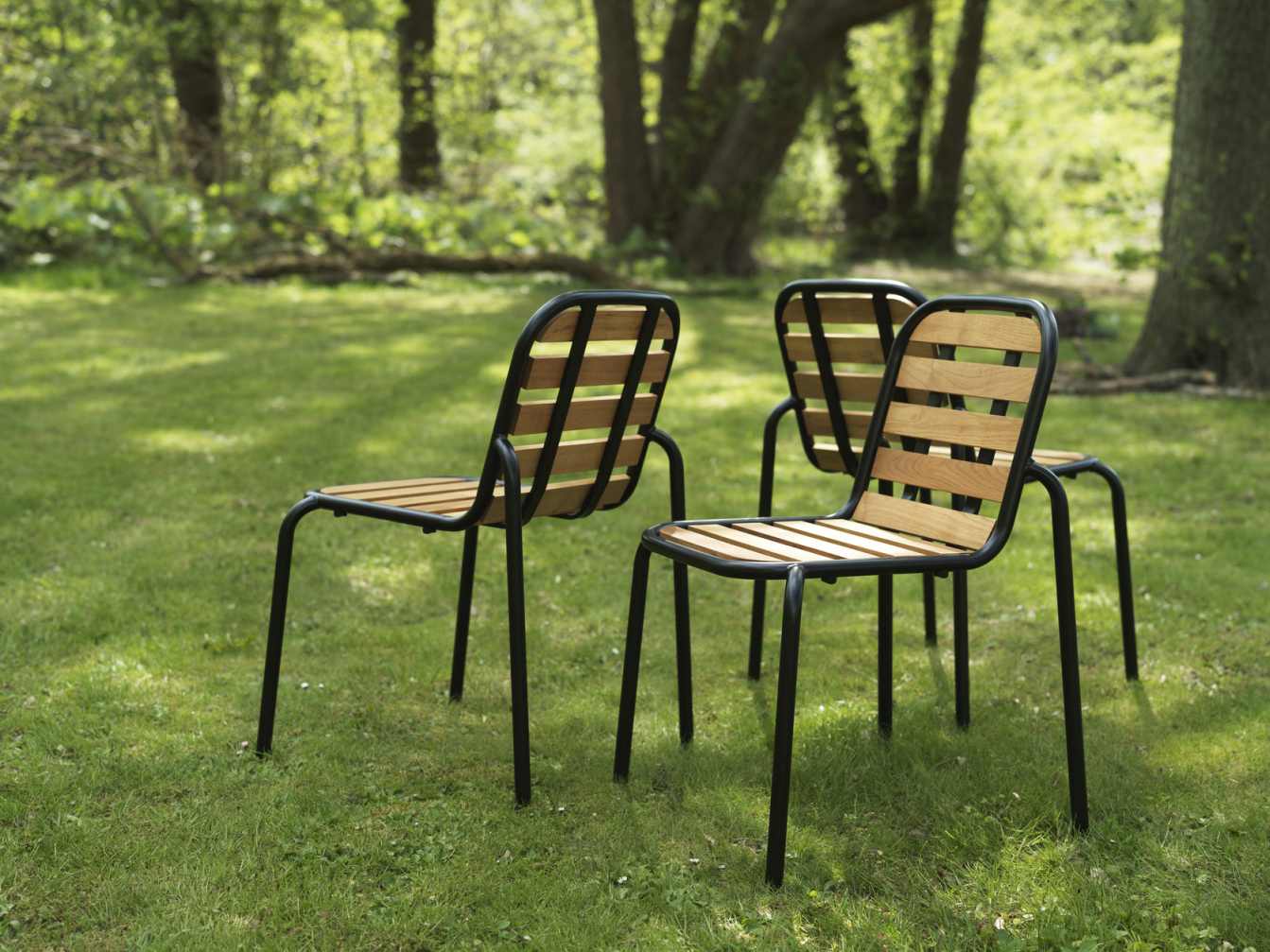 Drei Normann Copenhagen Vig Chair Wood Stühle auf Rasen, modernes Design für den Garten.