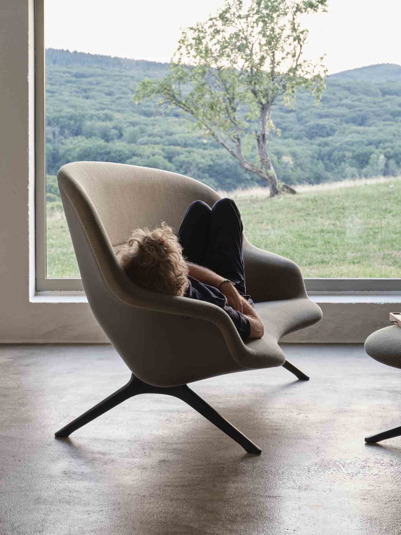 Mann entspannt im Abalon Sessel von Vitra mit Hocker und Blick auf die Natur.