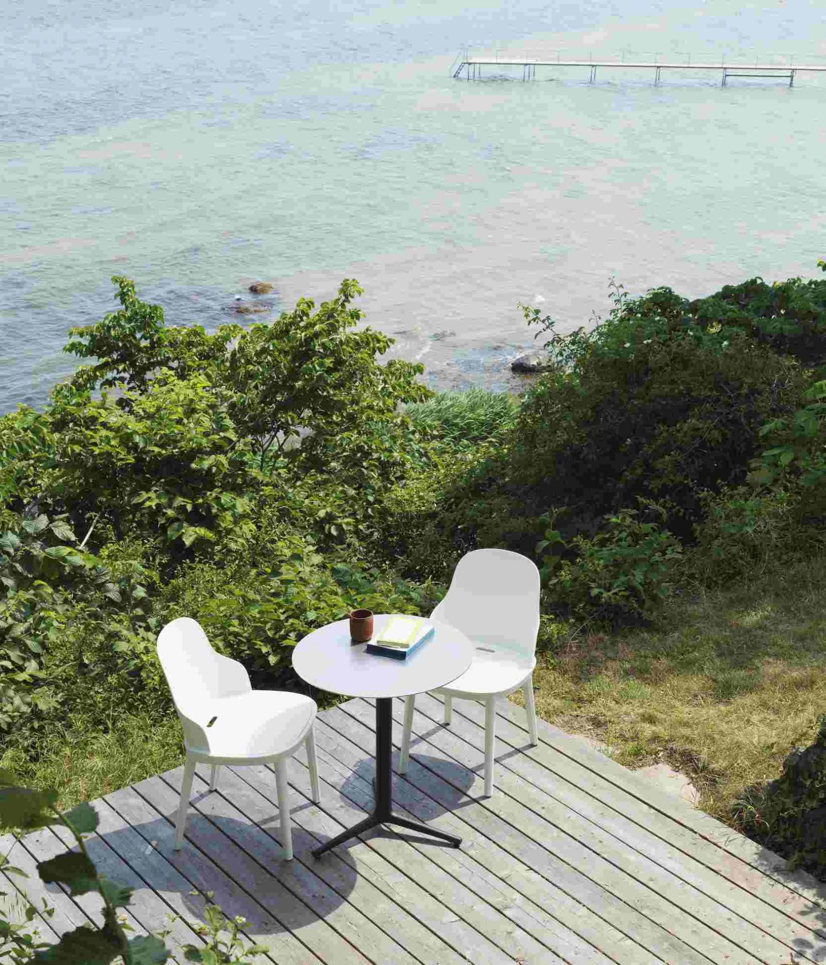Zwei weiße Allez Chair Stühle von Normann Copenhagen mit kleinem Tisch auf Holzterrasse am Meer.