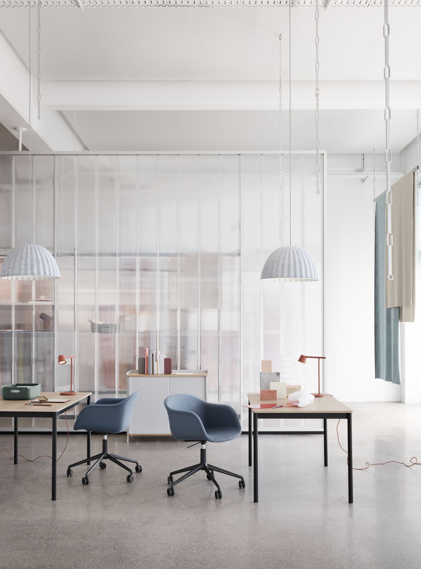 Heller Raum mit zwei Base Table Round Tischen von Muuto und blauen Bürostühlen.