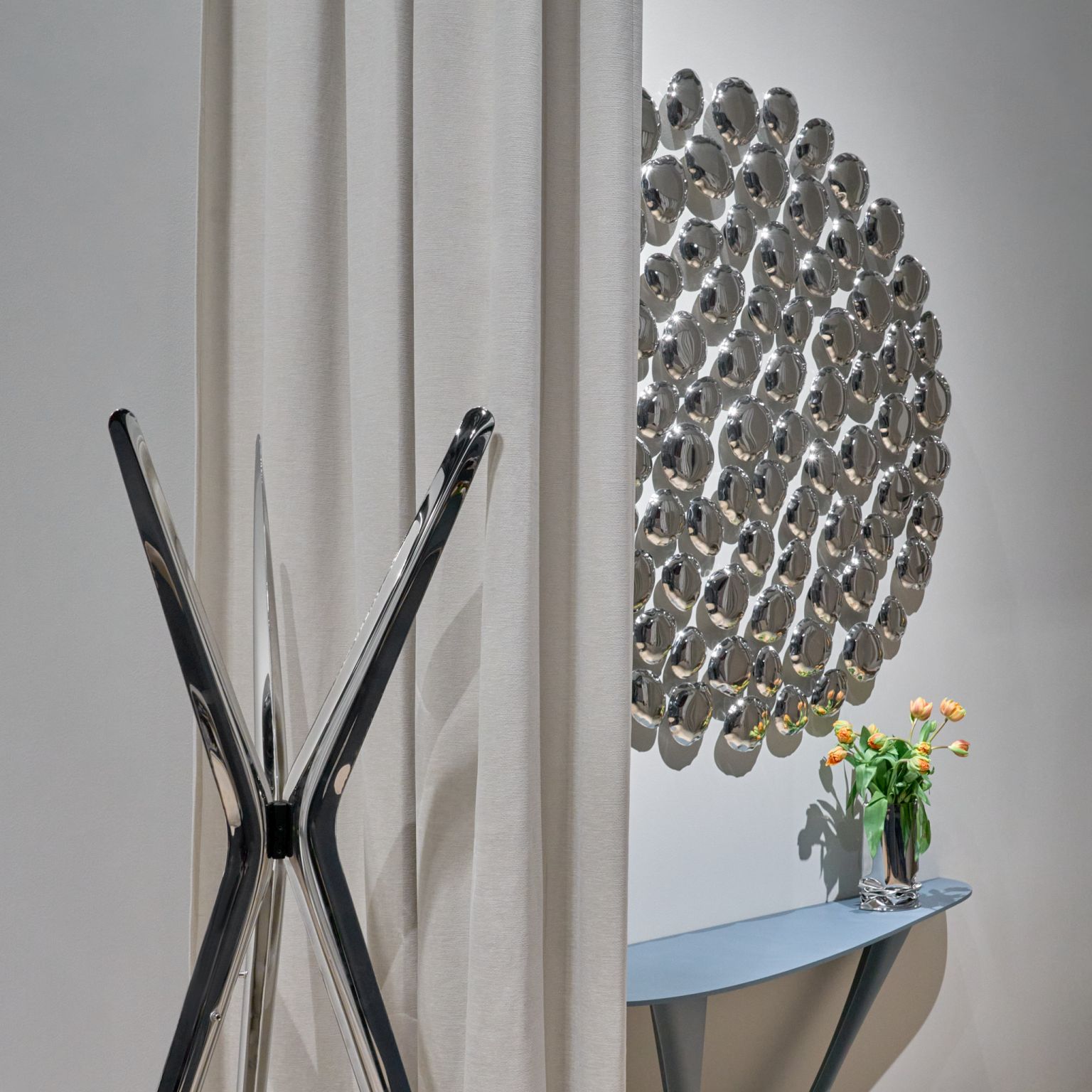 Moderner Snopek Garderobenständer von Zieta in Chromoptik neben Vorhang und Wanddekoration mit Tisch und Blumen.