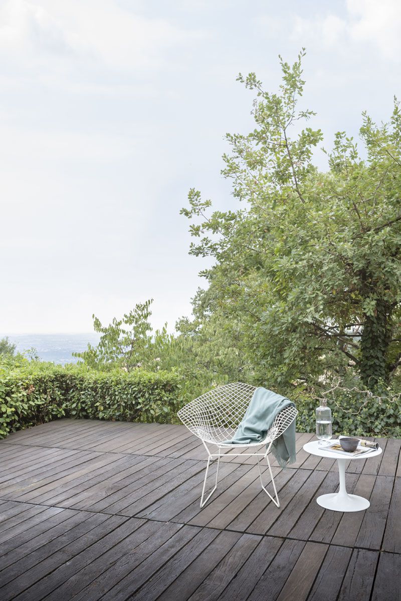 Bertoia Diamond Sessel Outdoor von Knoll International auf Holzterrasse mit Beistelltisch und Meerblick.