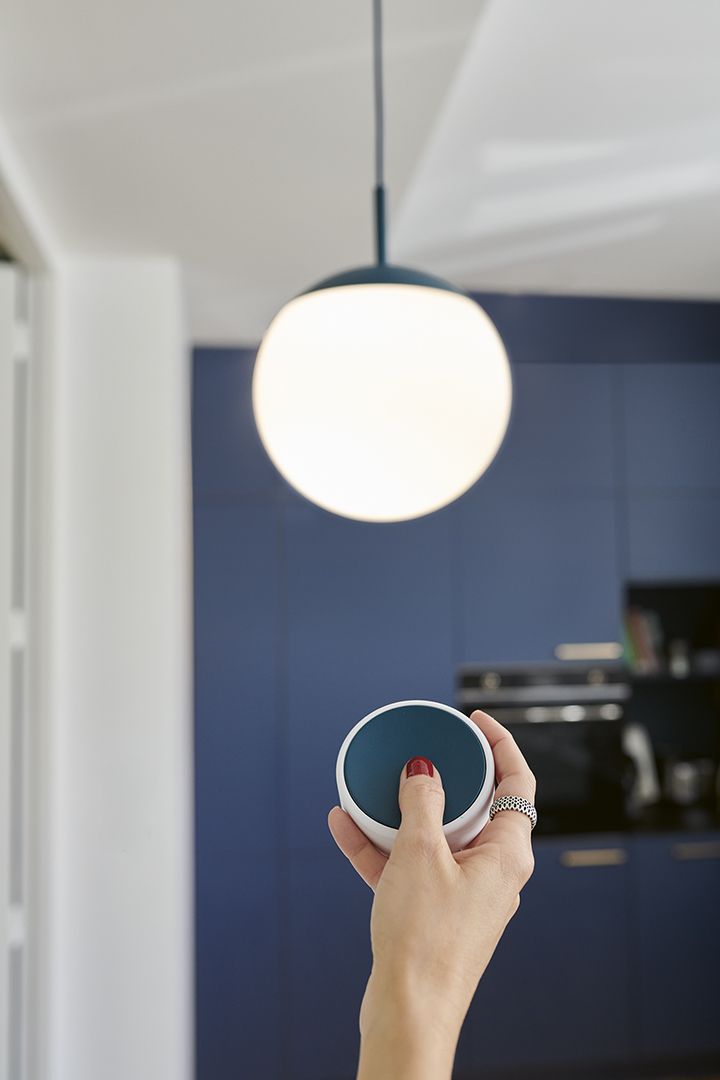 Mooon Pendelleuchte Ø 25 cm von Fermob mit Fernbedienung in der Hand. Moderne Hängelampe.