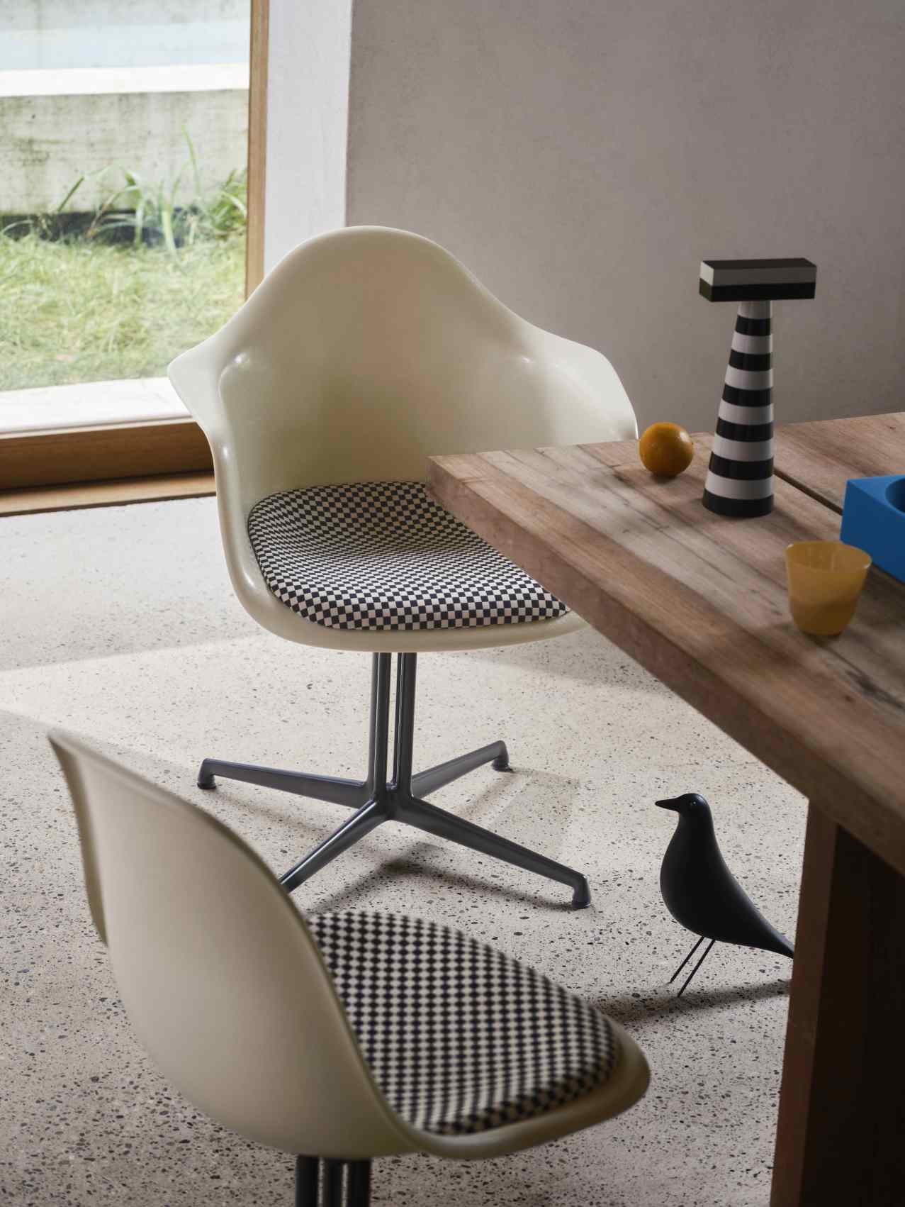 Eames House Bird Skulptur aus Esche, schwarz, von Vitra, auf einem Tisch neben Stühlen.