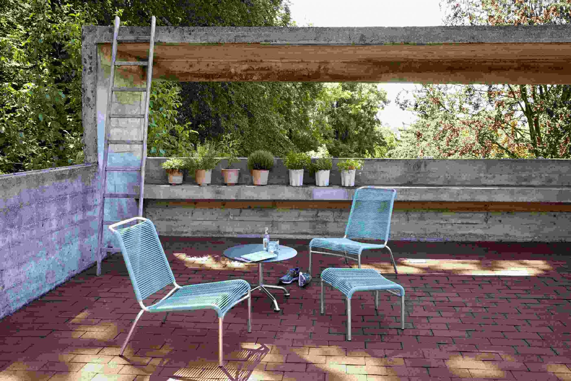 Altorfer Lounge Stuhl Outdoor Embru: Zwei blaue Loungesessel und ein Hocker auf einer Terrasse.
