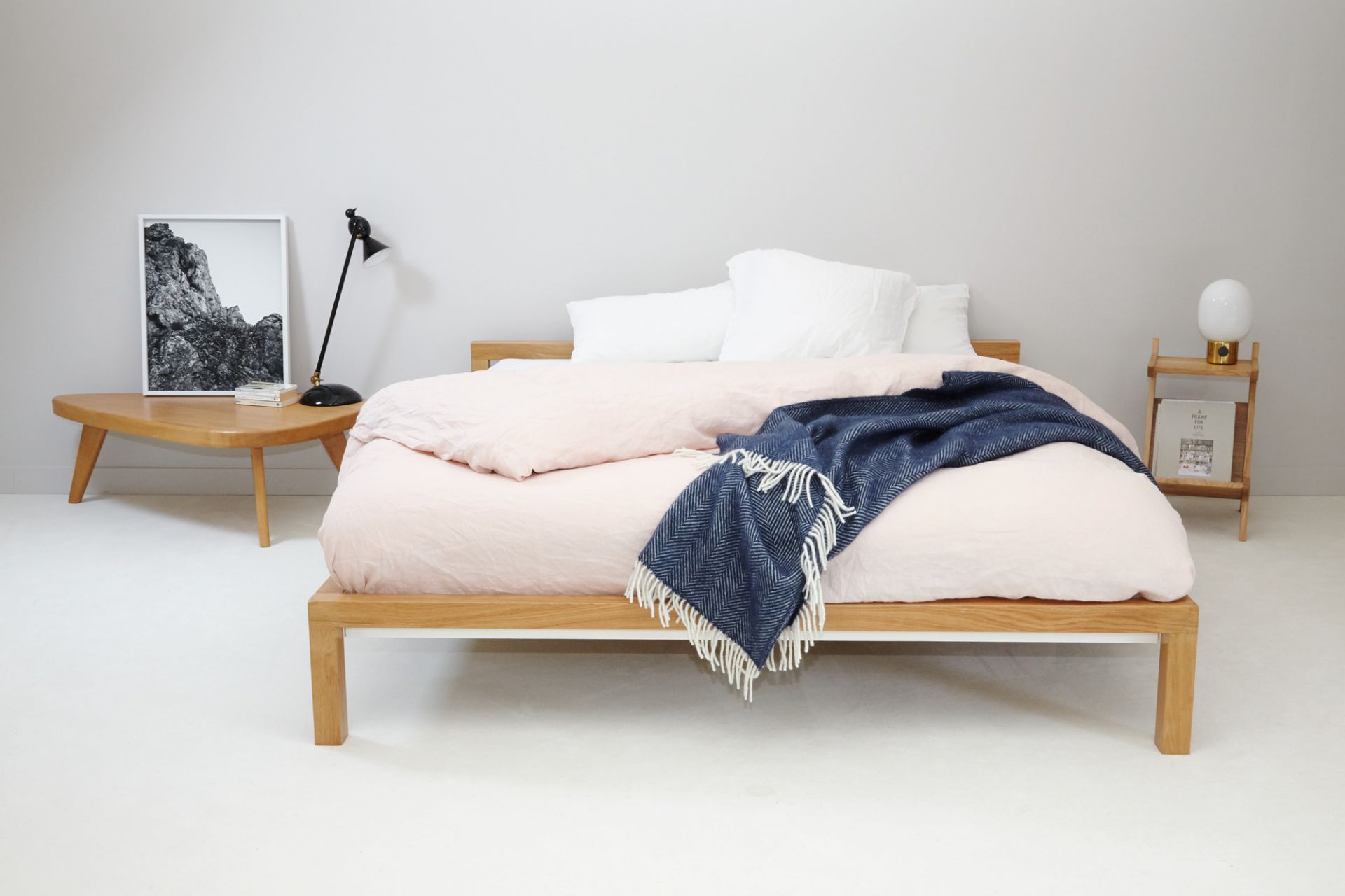 Hans Hansen Pure Bett Eiche 180x200 cm mit rosa Bettwäsche und blauer Tagesdecke im Schlafzimmer.