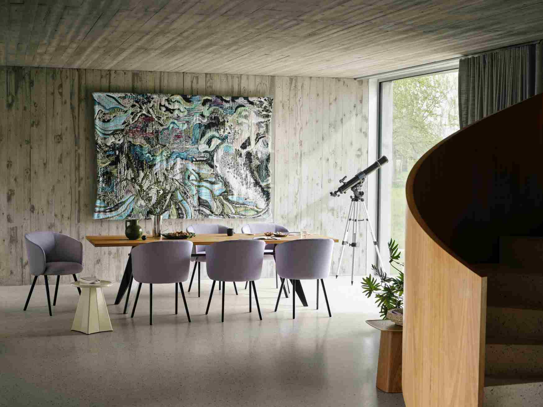 Esszimmer mit Holztisch, lila Stühlen und einem Vitra Tabouret Métallique Hocker als Beistelltisch.