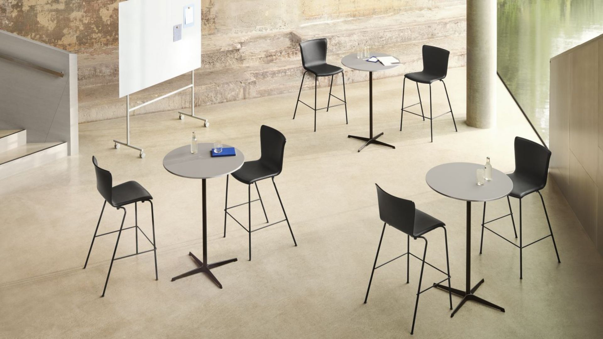 Mehrere graue Zirkular Stehtische von Fritz Hansen mit schwarzen Barhockern in einem modernen Büroraum.