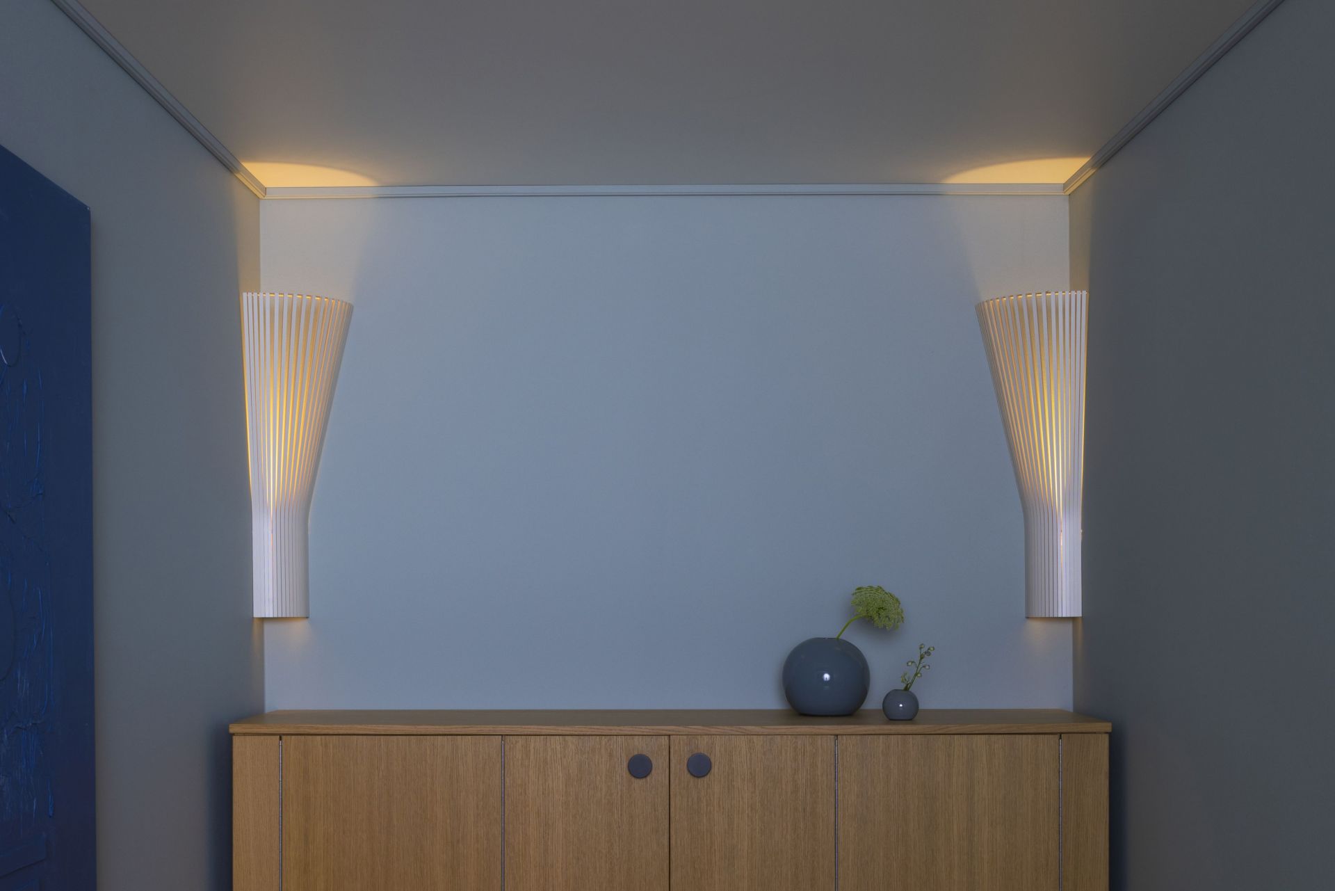 Secto 4236 Eckleuchte von Secto Design, zwei skandinavische Designleuchten aus Holz an einer blauen Wand.