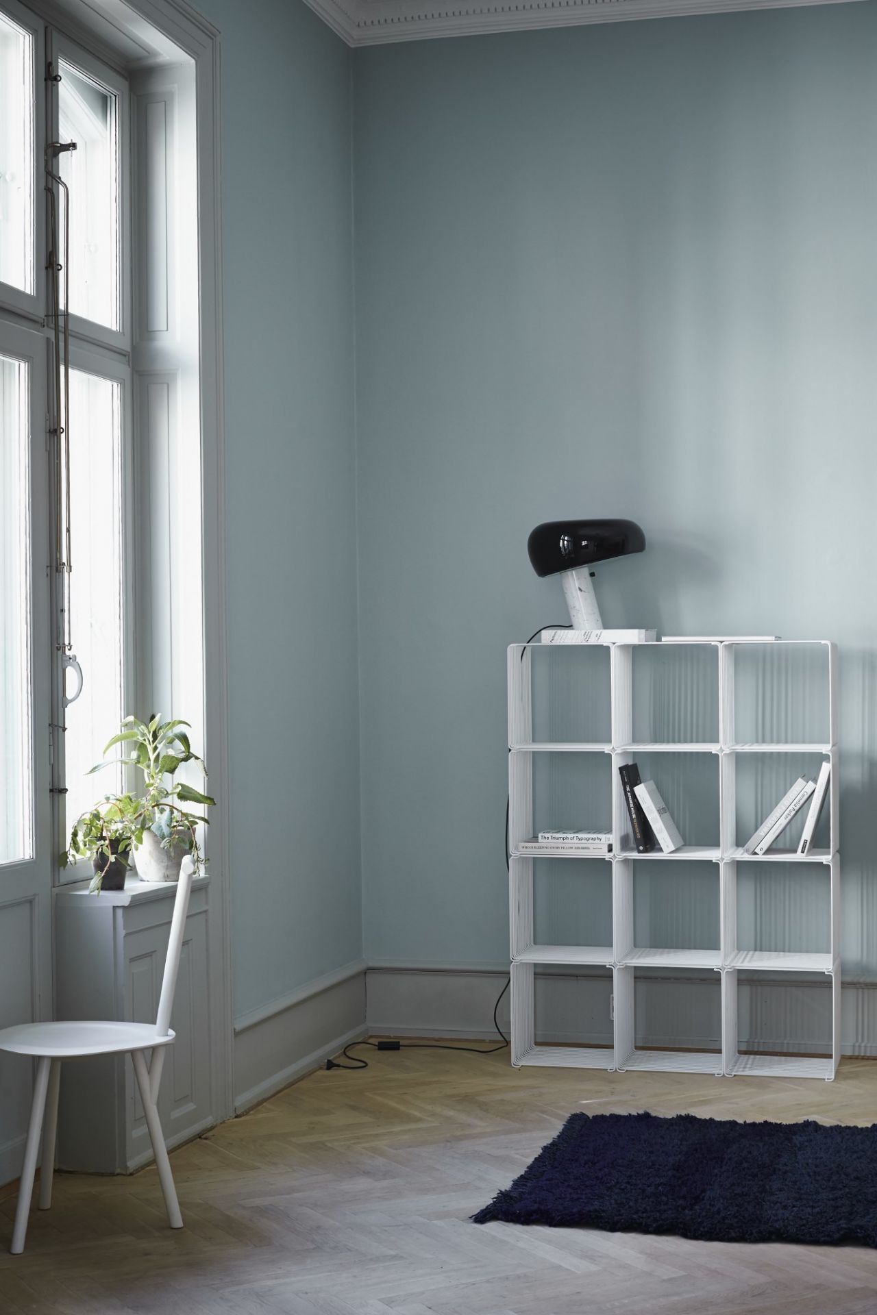 Helles Zimmer mit weißem Montana Wire Cube Drahtregal, das als Bücherregal und Ablage dient.