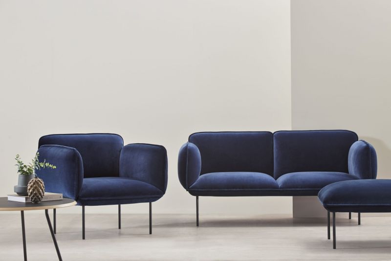 Soround Couchtisch von Woud, charcoalfarben, rund, mit Dekoration, vor einem blauen Sofa und Sessel.