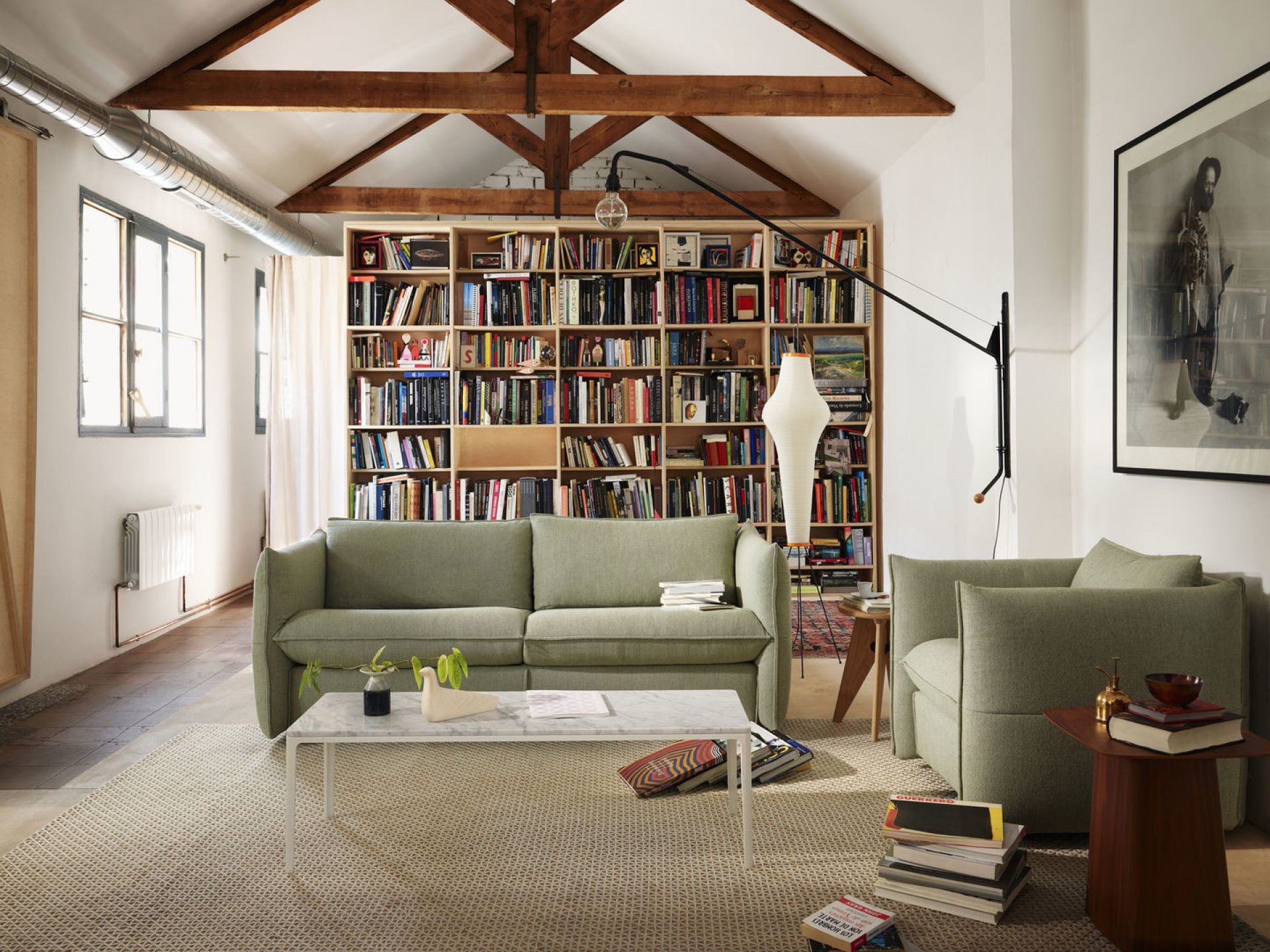 Wohnzimmer mit grünem Sofa, Sessel, Bücherregal und Marmor-Couchtisch für gemütliches Wohnen.