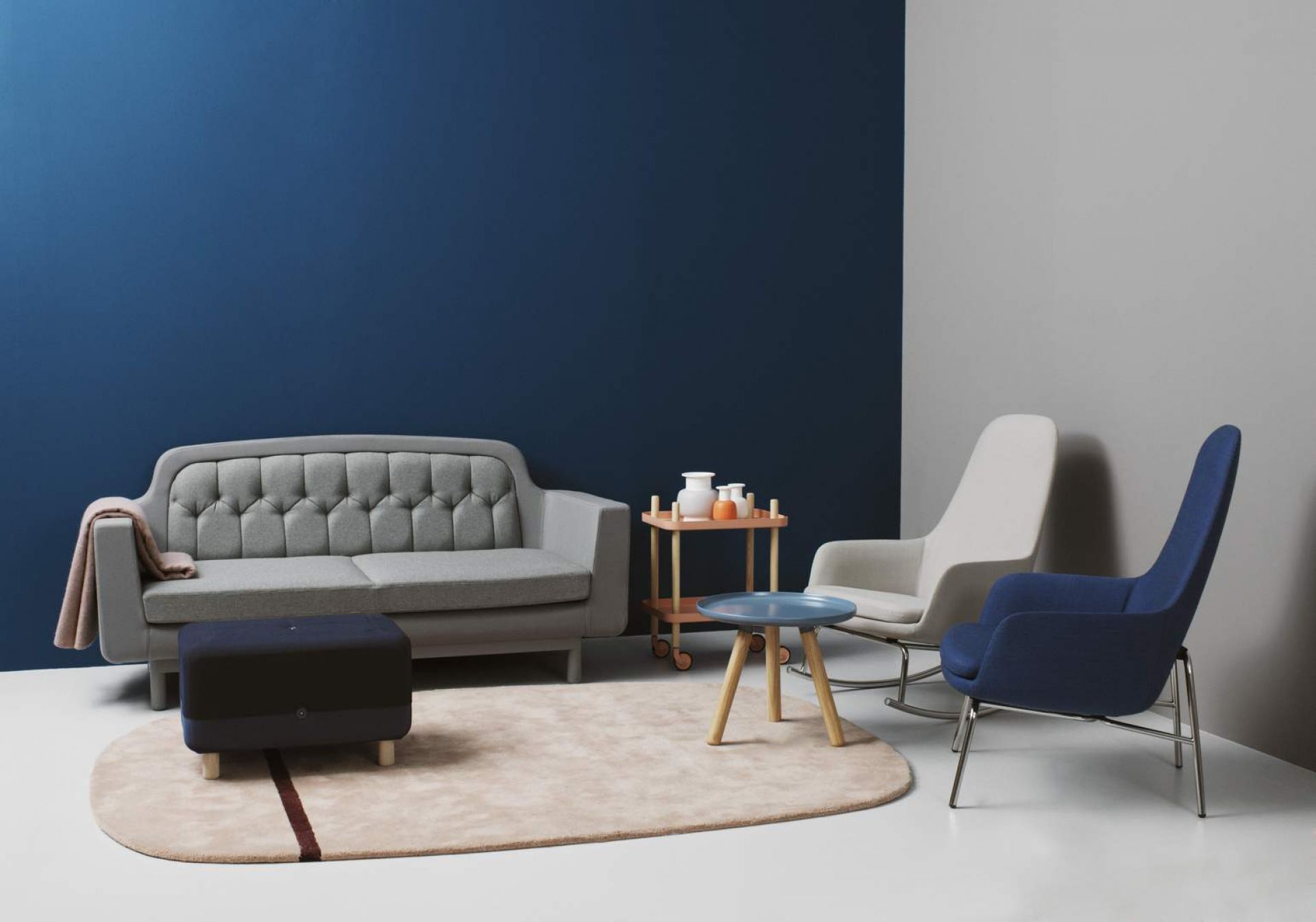 Wohnzimmer-Szene mit Normann Copenhagen Era Lounge Sessel hoch in Blau und Grau, Sofa und Teppich.