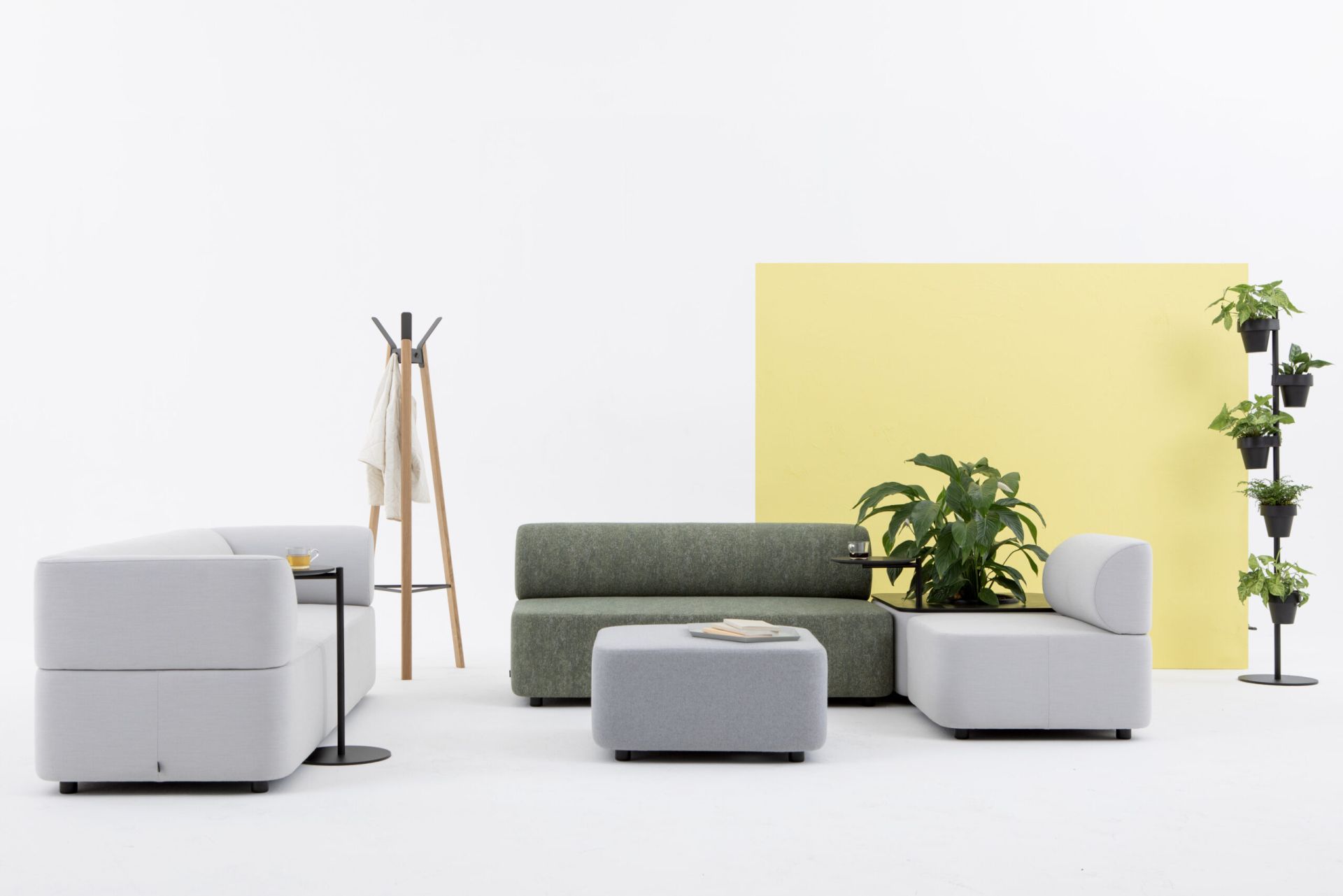 Mezza Sitzelement von Cascando: Modulares Sofa in Grau und Grün mit Beistelltisch und Pflanzen.