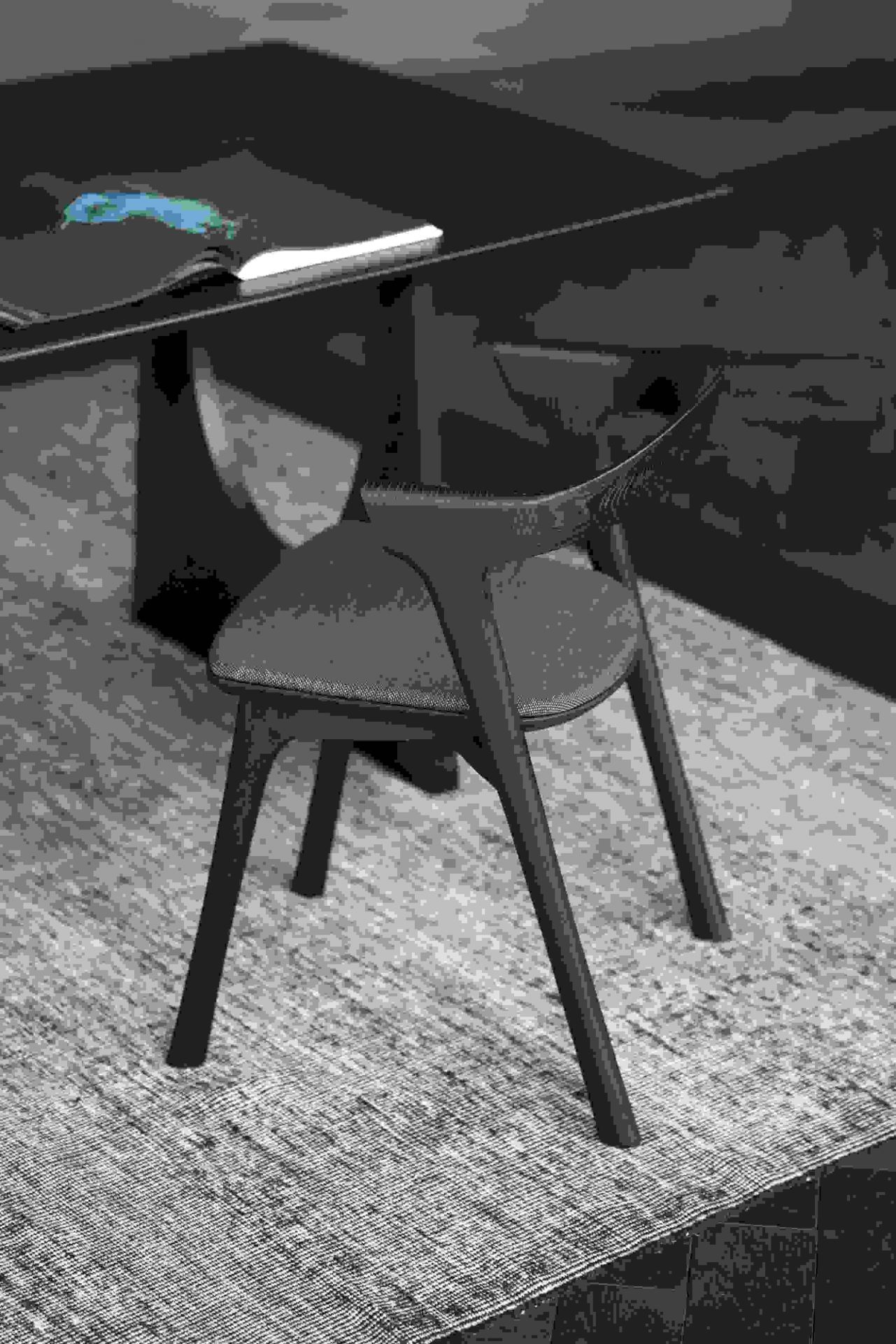 Nahaufnahme des Bok Stuhls von Ethnicraft, braunes Eichenholz mit schwarzem Stoffbezug, minimalistisches Design.