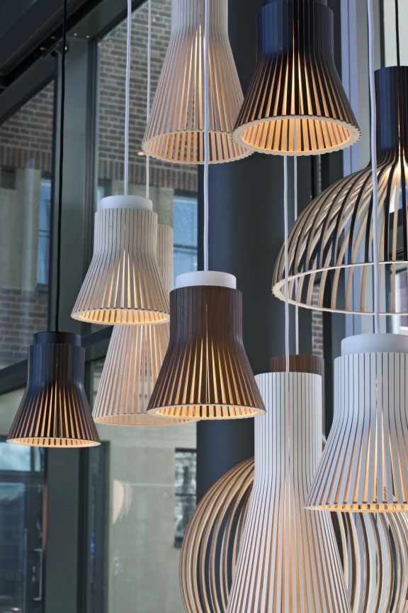 Nahaufnahme verschiedener Secto Design Pendelleuchten aus Holz in Weiß, Birke und Schwarz.