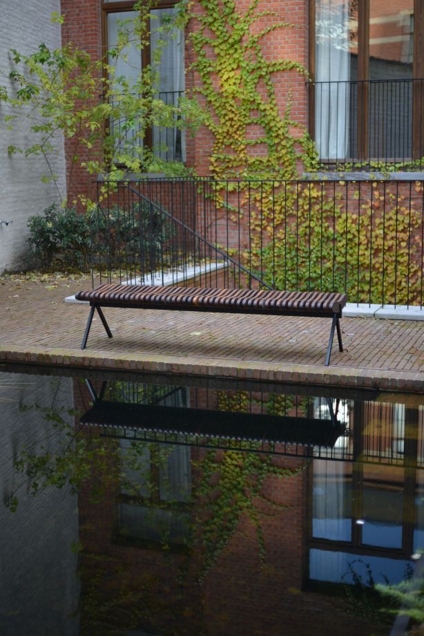 Prelude Bank aus Holz und Metall am Wasser, moderne Parkbank für den Außenbereich.