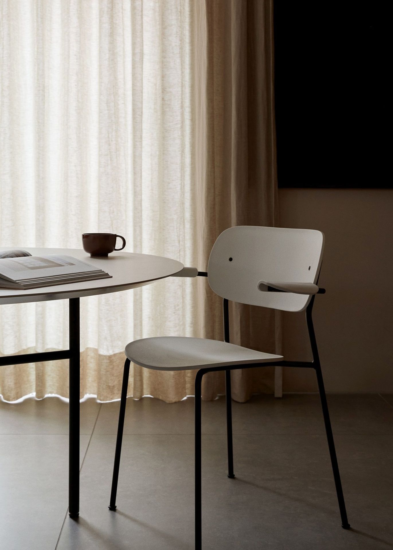 Audo Copenhagen Co Dining Chair Stuhl in Weiß mit schwarzem Metallgestell am Esstisch.