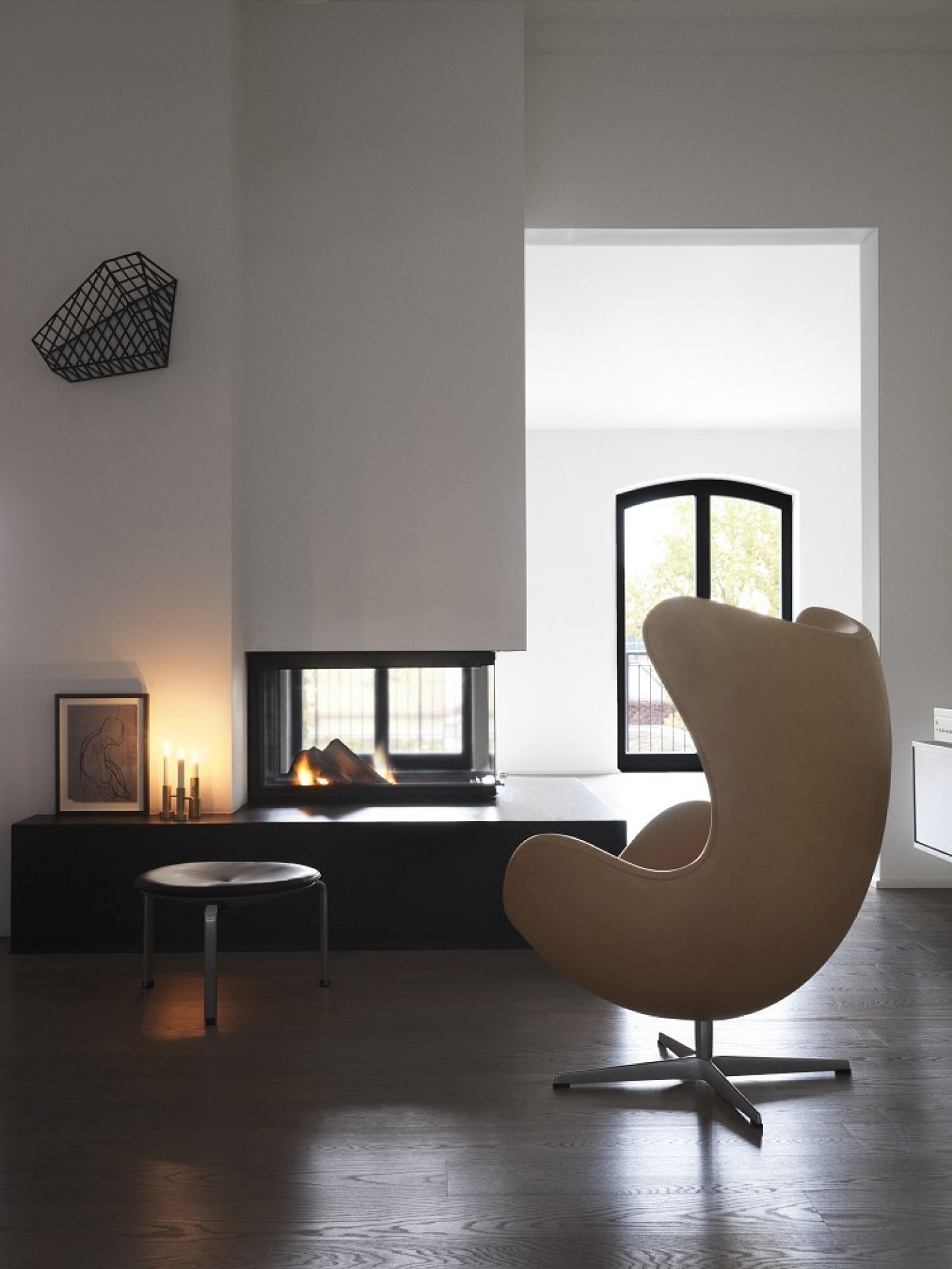 Beiger Sessel und PK33 Hocker von Fritz Hansen vor modernem Kamin in minimalistischem Wohnzimmer.