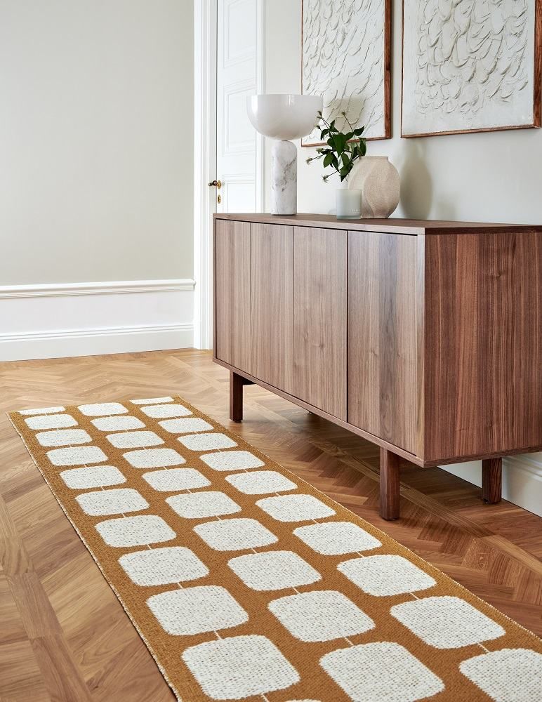 Pappelina Sten Teppich 70x200 cm in Gold und Weiß mit grafischem Muster im Flur.