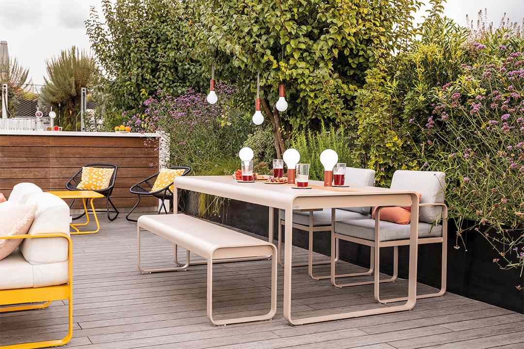 Bellevie Sessel von Fermob auf einer Terrasse mit Outdoor-Möbeln und üppigem Grün.