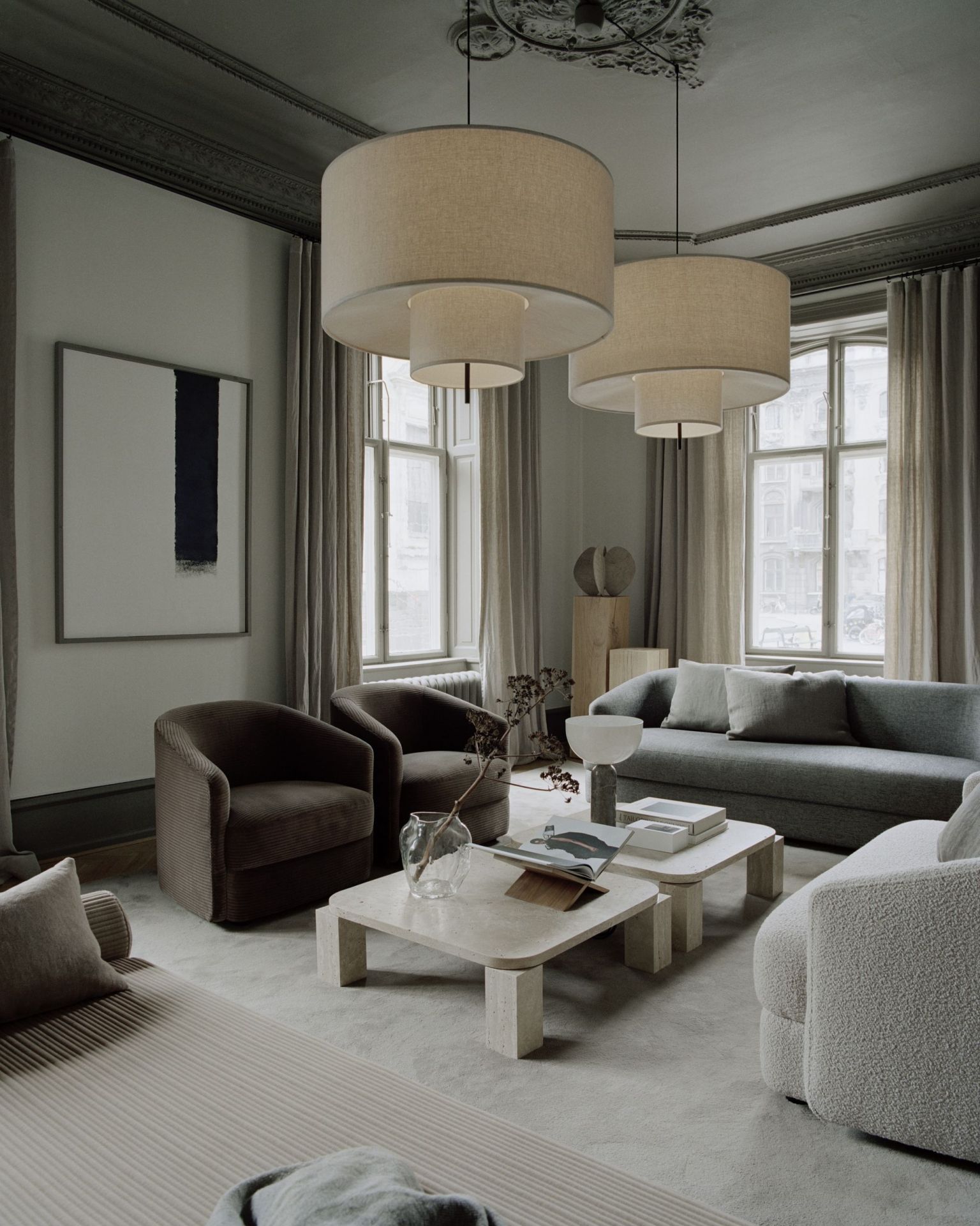 Wohnzimmer Interieur mit New Works Atlas Couchtisch aus Travertin, Sofa, Sessel und Pendelleuchten.