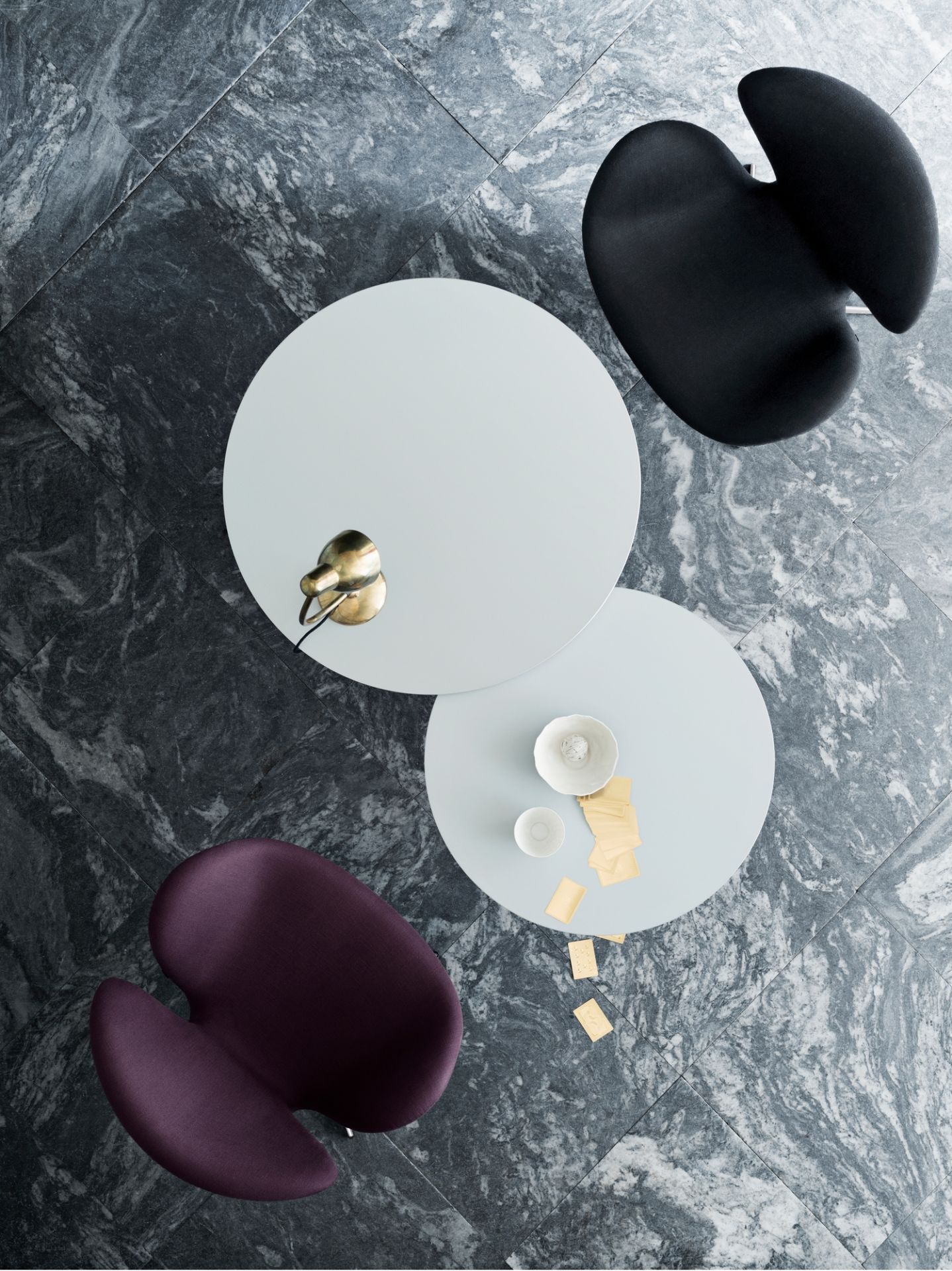 Fritz Hansen Couchtischserie Rund, zwei Tische mit Stühlen auf grauem Marmorboden, Vogelperspektive.