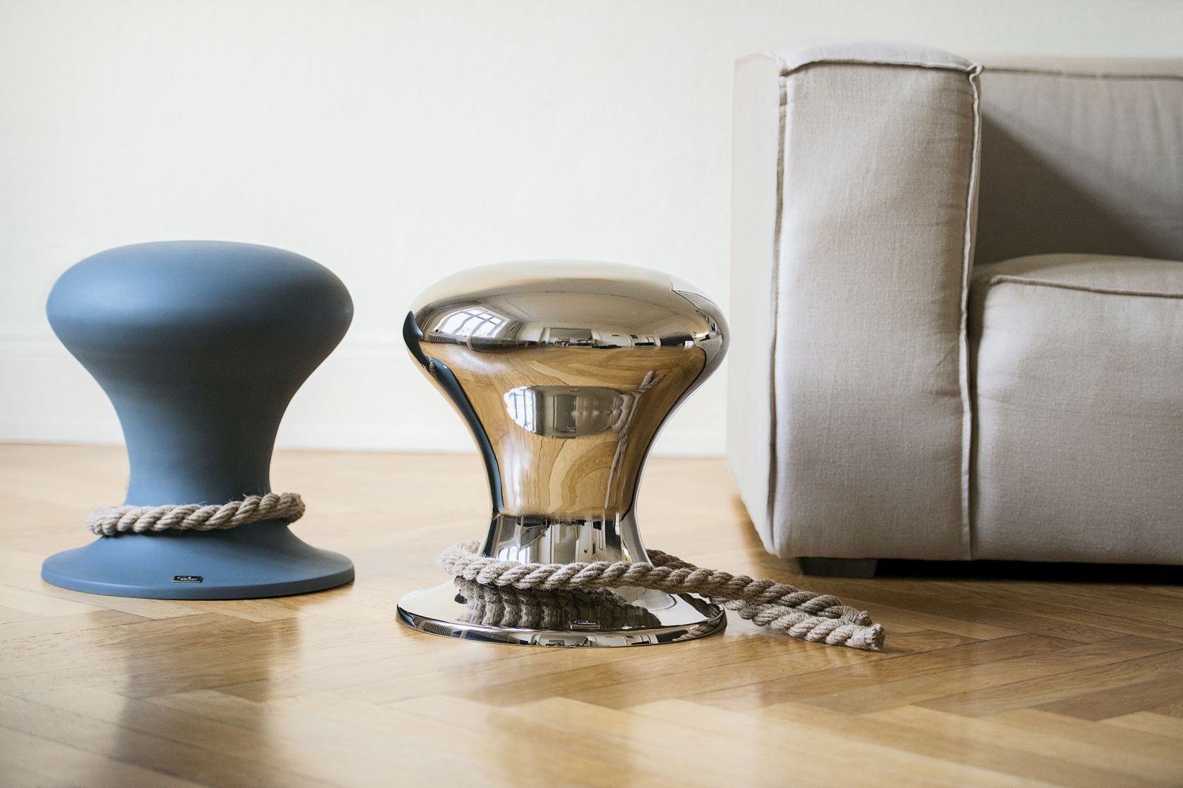 Hamburger Hocker von Philippi, poliert, mit Seil auf Parkettboden neben einem Sofa.