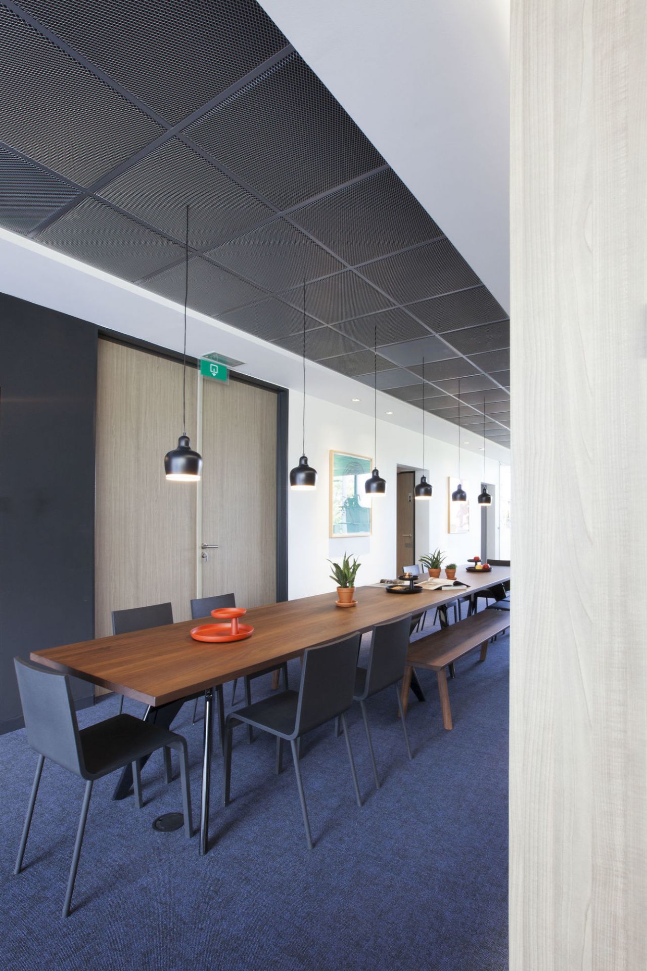 .03 Stuhl von Vitra in einem modernen Büroraum mit langem Holztisch und Pendelleuchten.