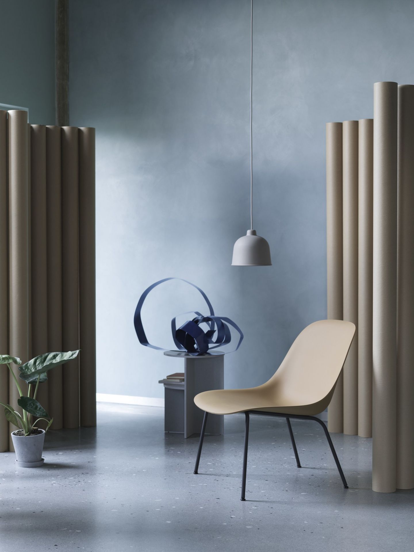 Helle Muuto Grain Pendelleuchte über beigem Stuhl in modernem Raum mit Pflanzen und Dekoration.