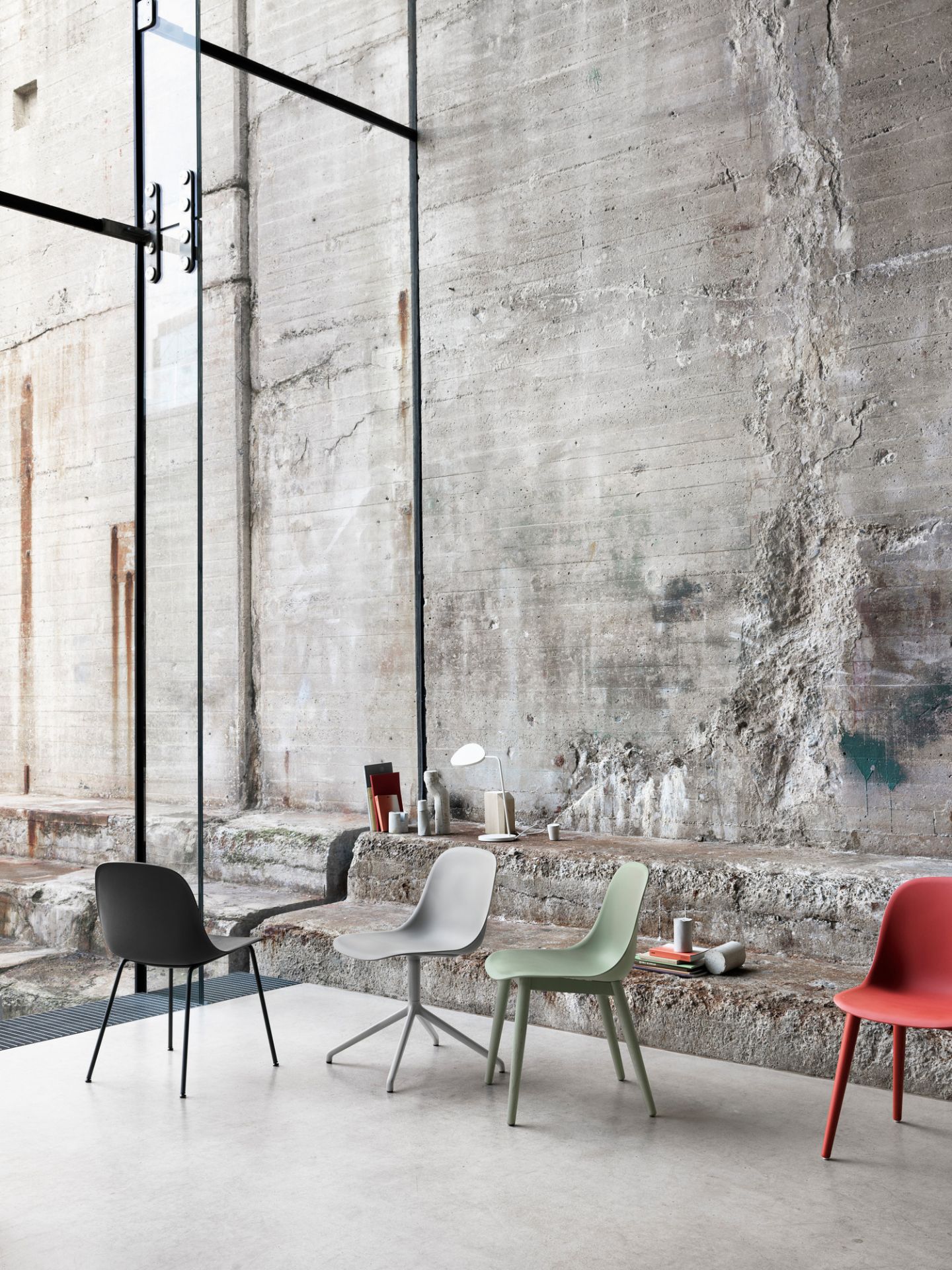 Mehrere Fiber Side Chairs von Muuto in verschiedenen Farben vor einer Betonwand.