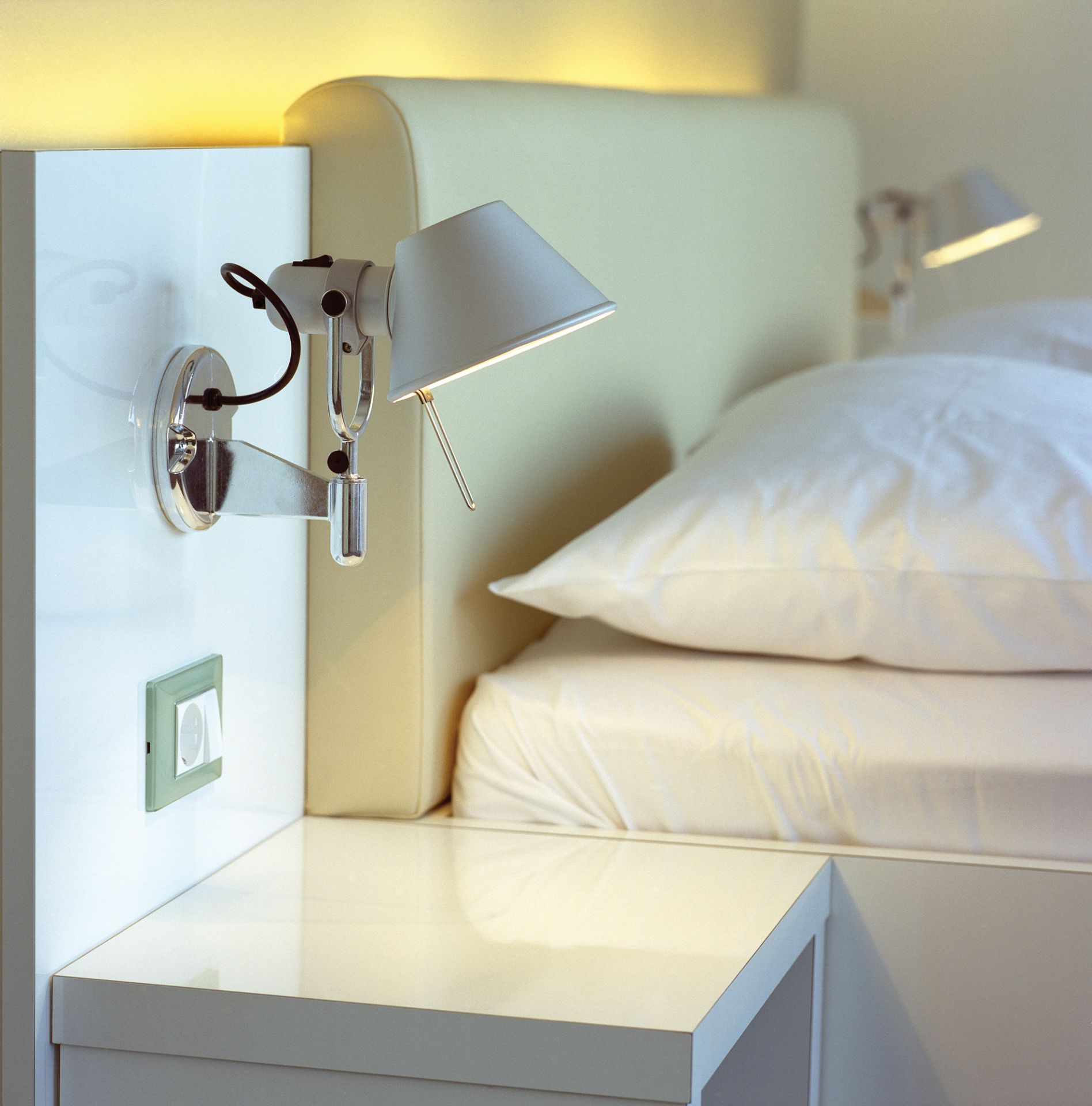 Nahaufnahme einer modernen Tolomeo Faretto Wandleuchte aus Aluminium von Artemide neben einem Bett.
