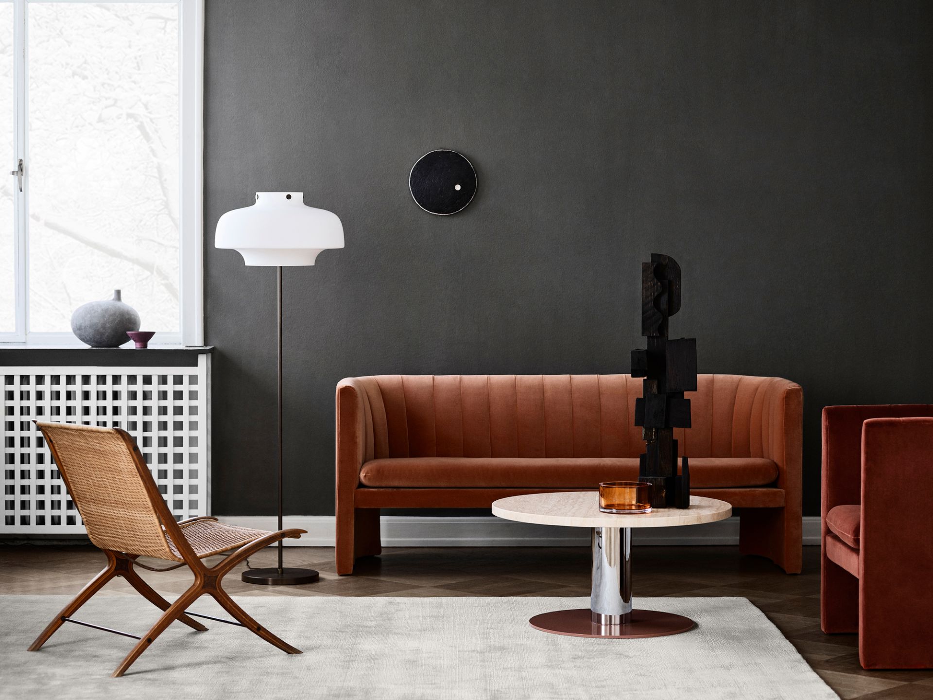 Wohnzimmer mit Loafer Sofa, Sessel, Teppich und Tisch in warmen Farben.