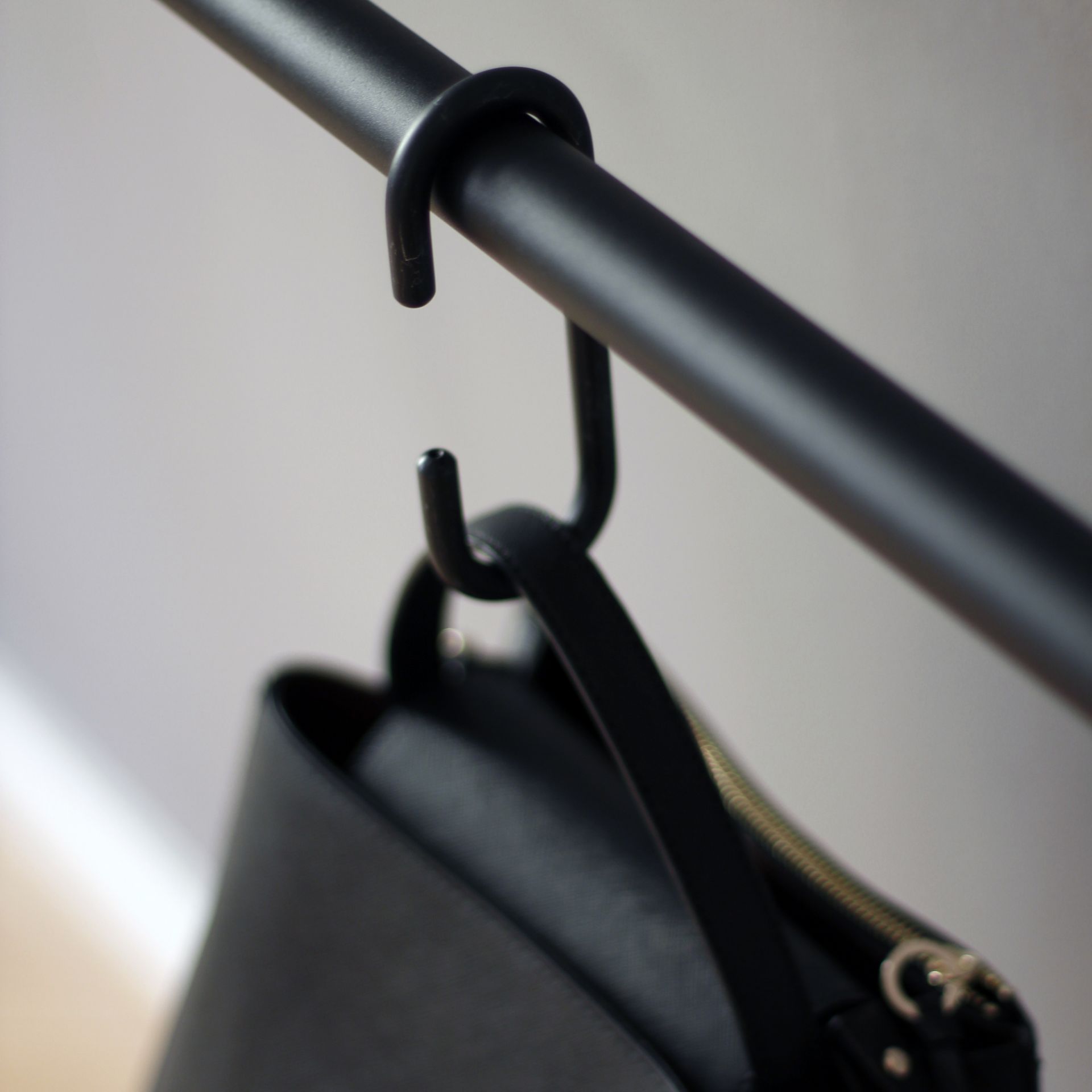 Detailaufnahme: Schwarze Handtasche hängt an der Roomsafari Leanon Anlehngarderobe. Moderne Garderobenlösung.