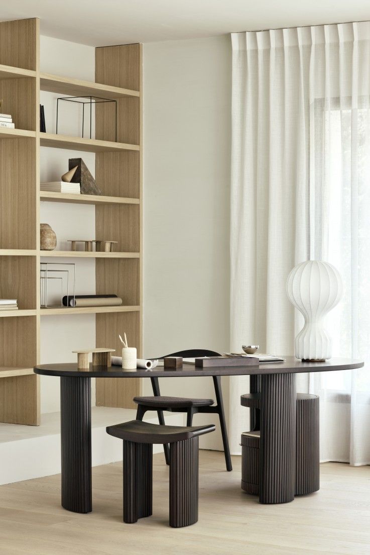 Ethnicraft Boomerang Schreibtisch aus dunklem Holz mit passendem Hocker und Stuhl in modernem Arbeitszimmer.