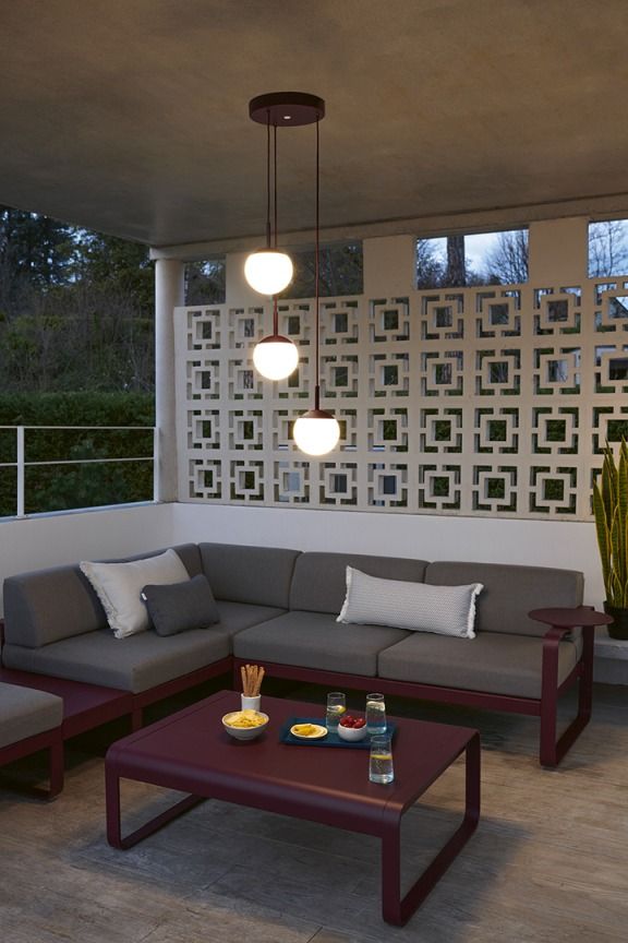 Mooon Triple Pendelleuchte von Fermob über Lounge-Bereich mit Sofa und Tisch im Außenbereich.