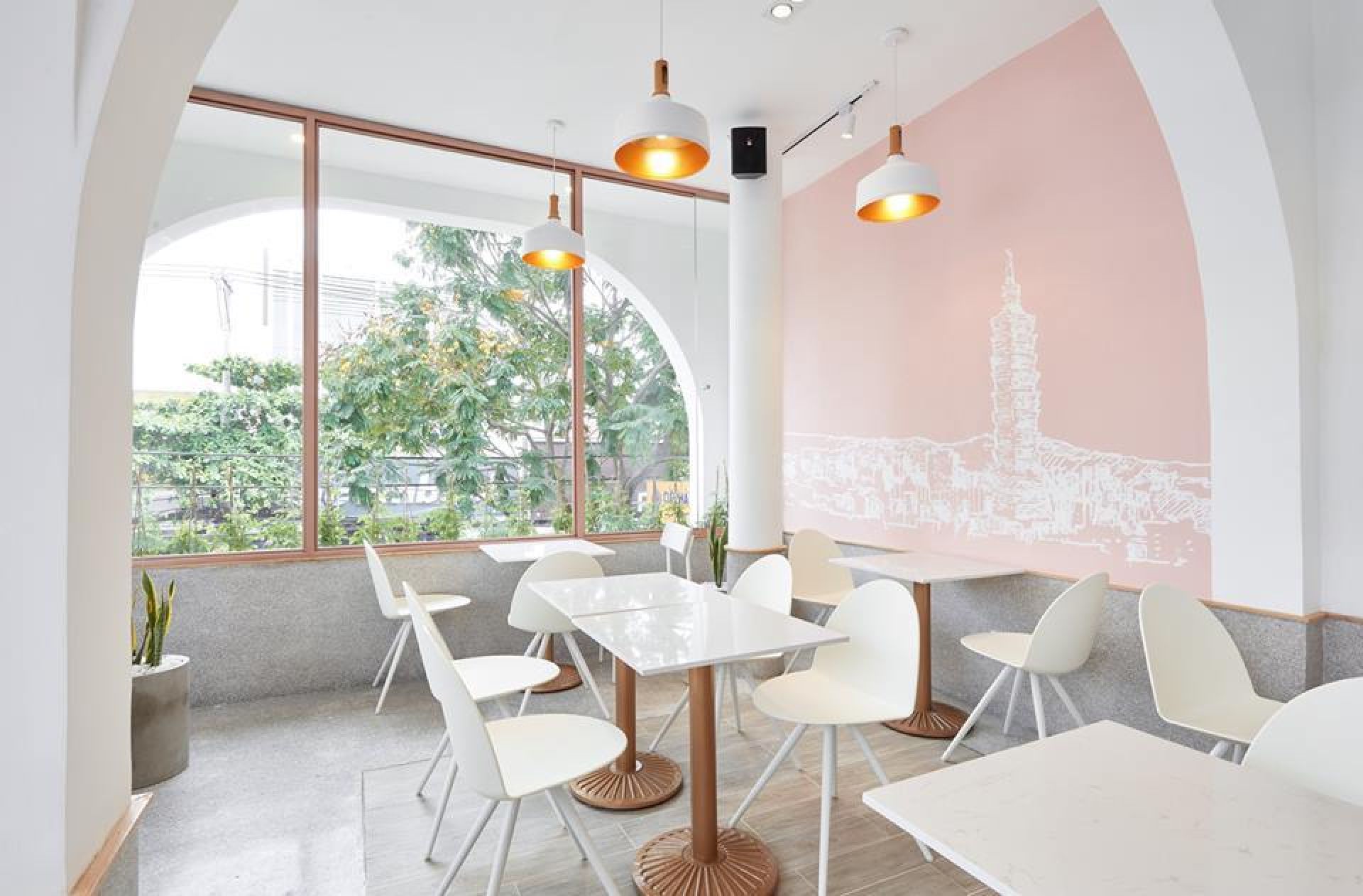 Innenaufnahme eines Cafés mit weißen Camel Stühlen von Segis und Tischen unter Pendelleuchten.
