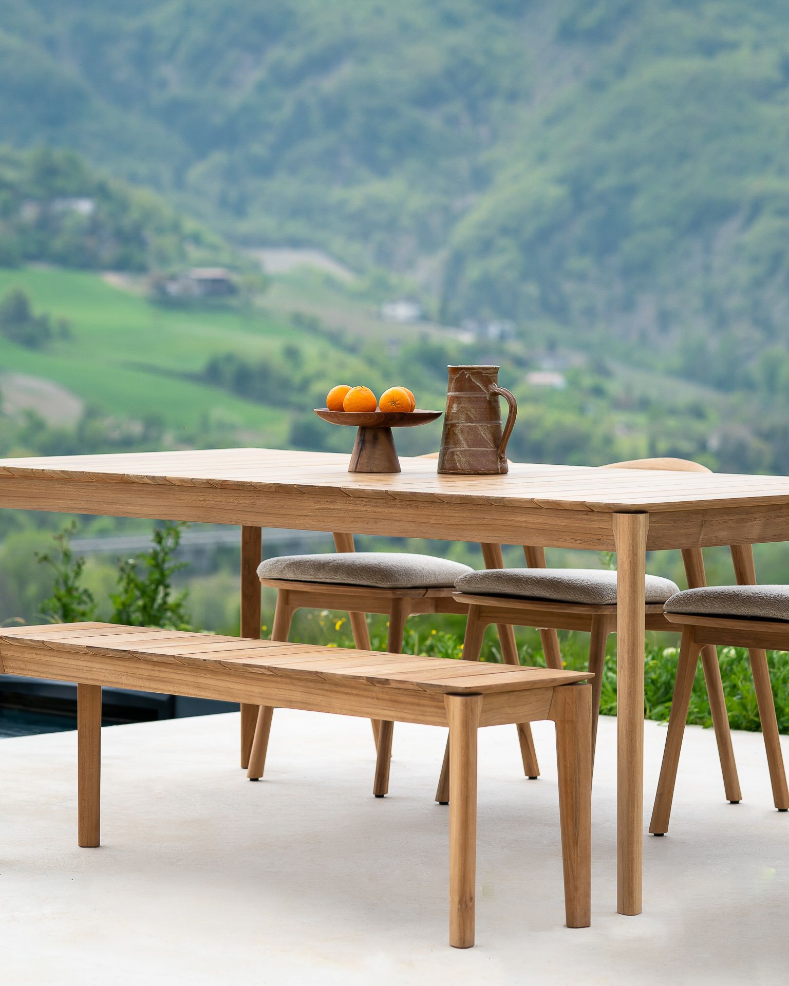 Bok Outdoor Bank und Esstisch aus Teakholz von Ethnicraft mit Bergpanorama im Hintergrund.